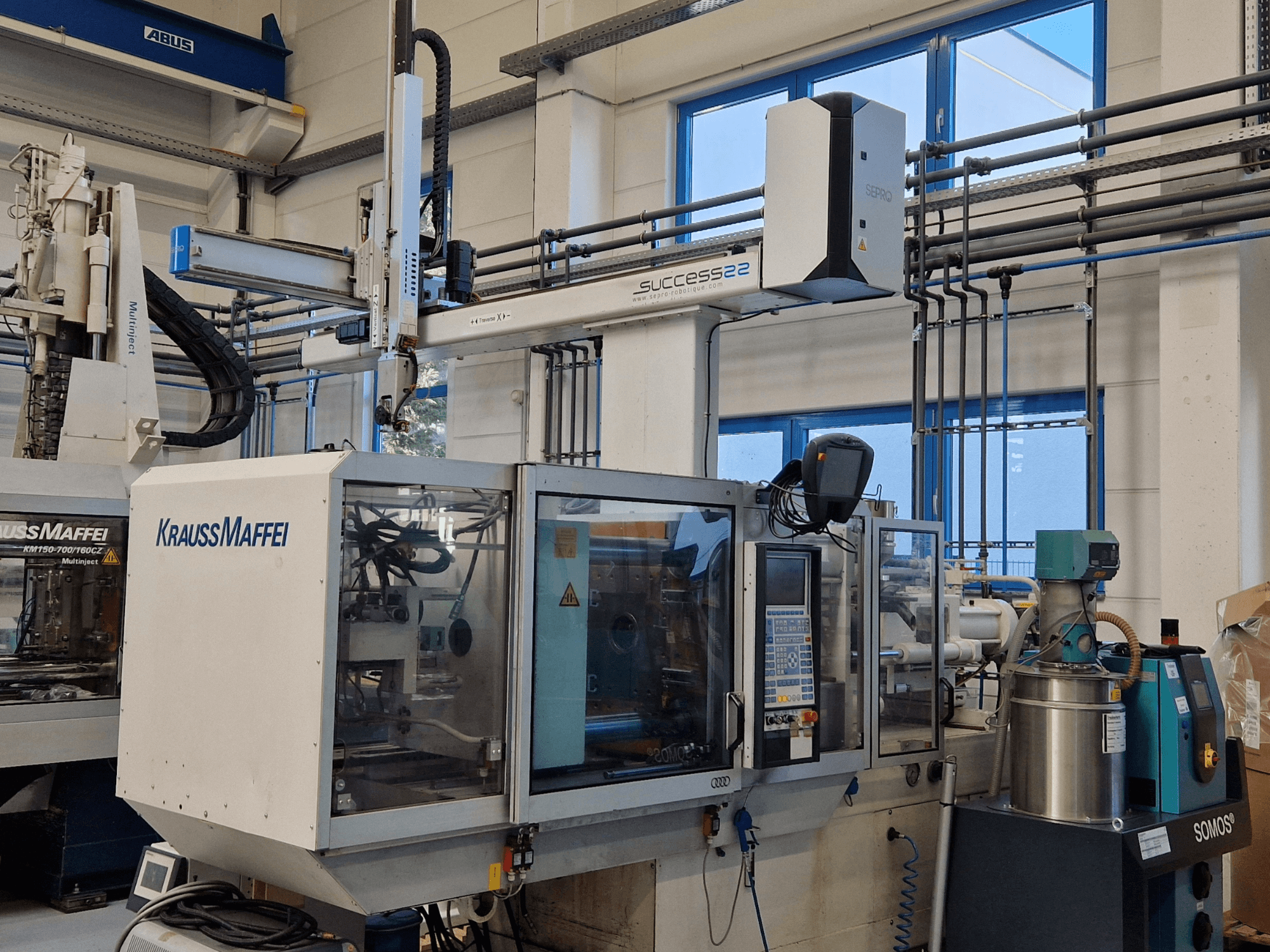 KraussMaffei Success 22 Spritzgießmaschine mit Bedienpult, von vorne gesehen in einer Werksumgebung.