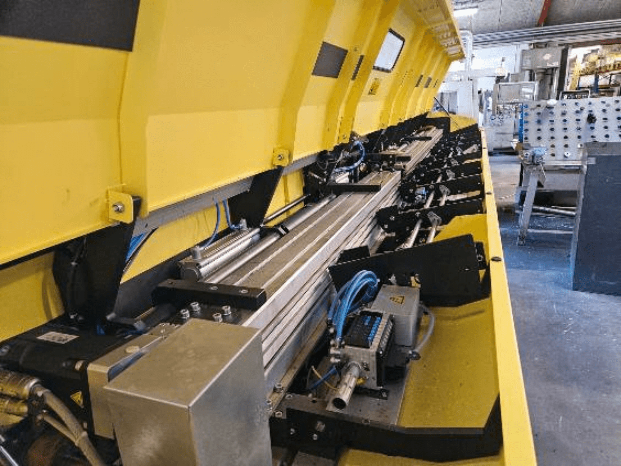 Nahaufnahme einer gelben hydraulischen Maschine mit Metallteilen und Förderbändern, mit Schläuchen und elektronischen Teilen.