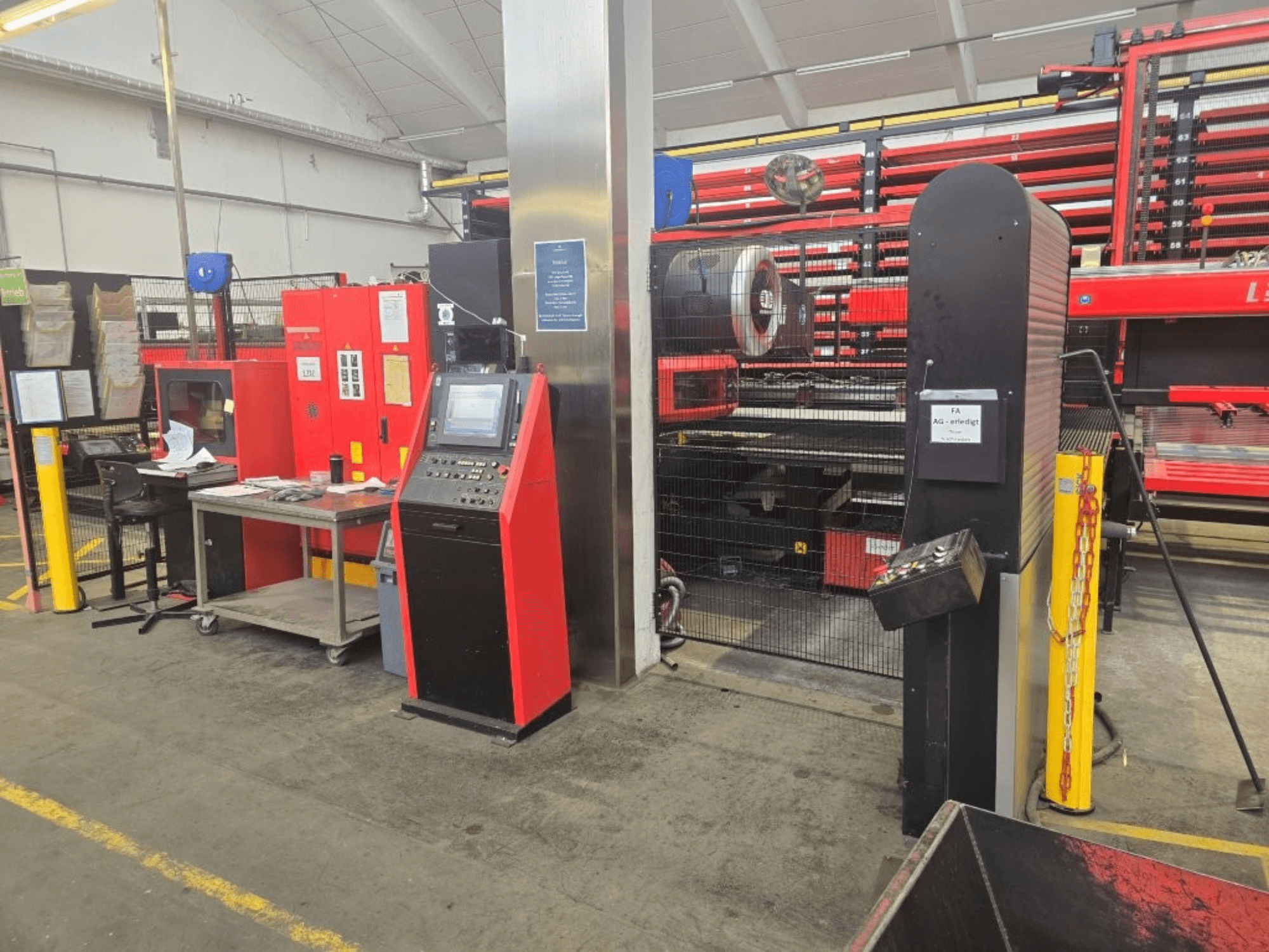 Vorderansicht der CNC-Stanzmaschine AMADA EMZ 3610 NT mit Bedienelementen und Schutzabdeckung in einer Werksumgebung.