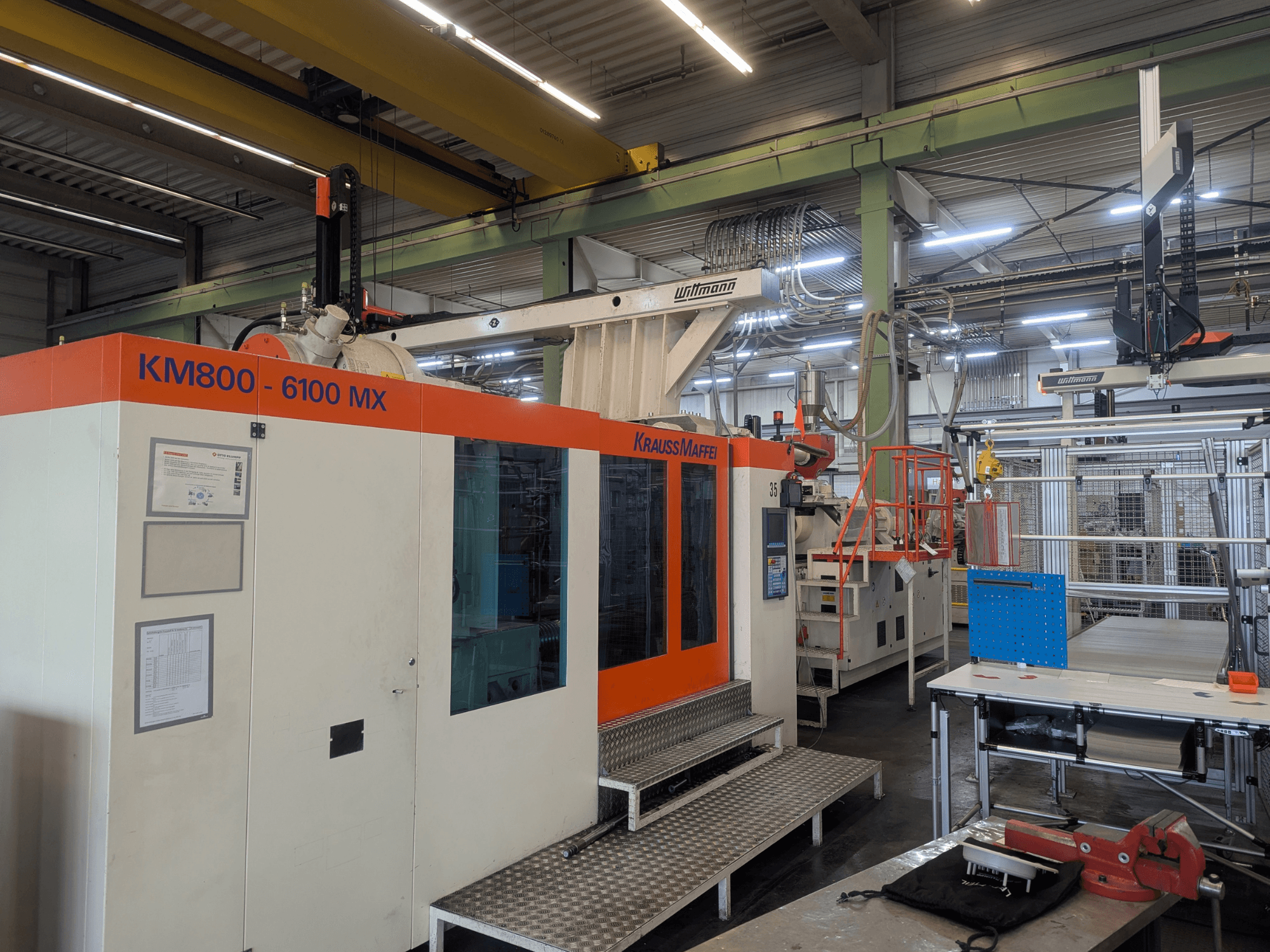 Hydraulische Spritzgießmaschine Krauss Maffei KM 800-6100MX, Vorderansicht, mit Bedienfeld und industrieller Einrichtung.