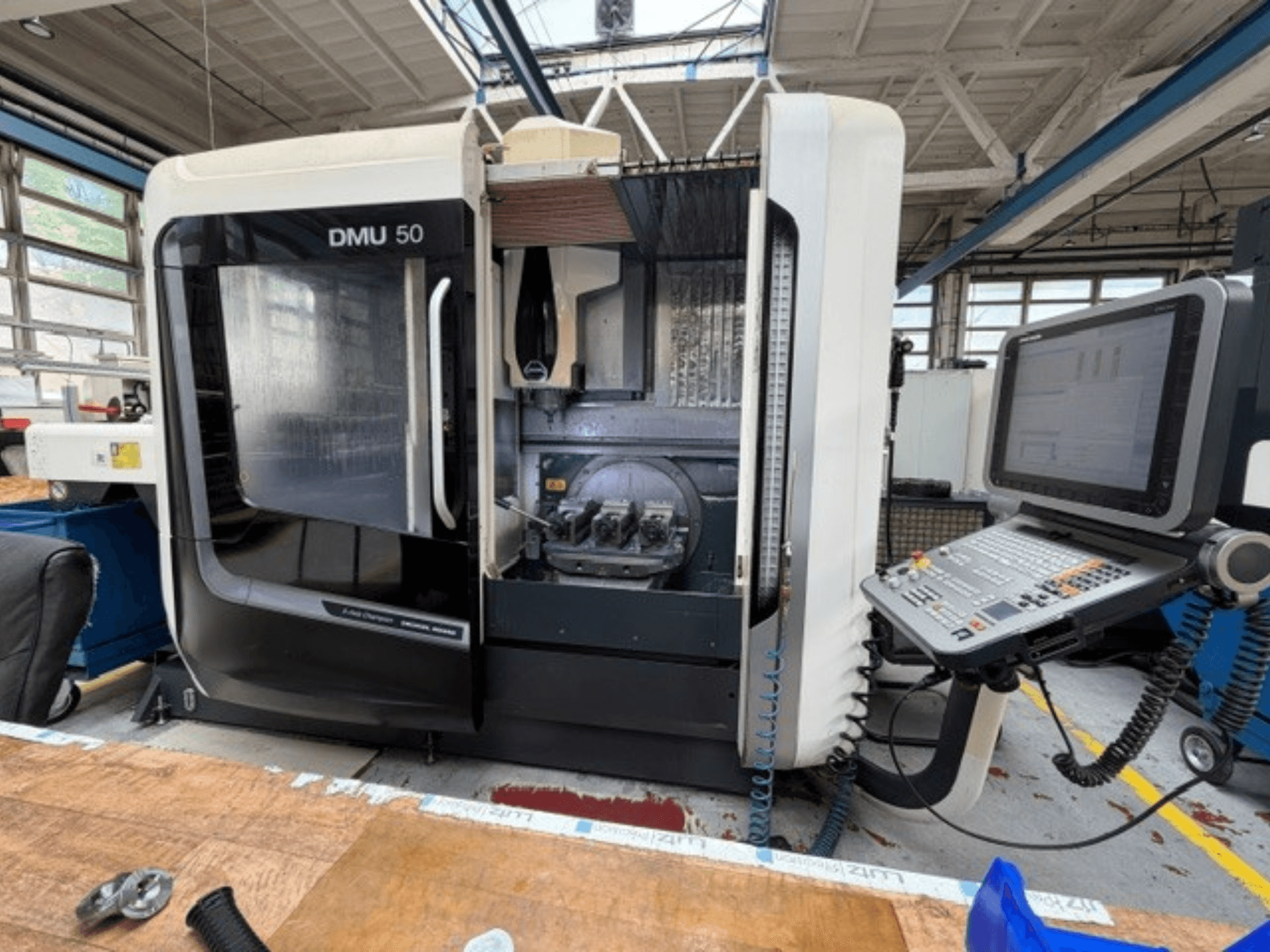 Das vertikale Bearbeitungszentrum DMG MORI DMU 50 der 3. Generation, von vorne gesehen, mit geöffneter Tür, sichtbarem CNC-Bedienfeld und dem Arbeitsbereich im Inneren.