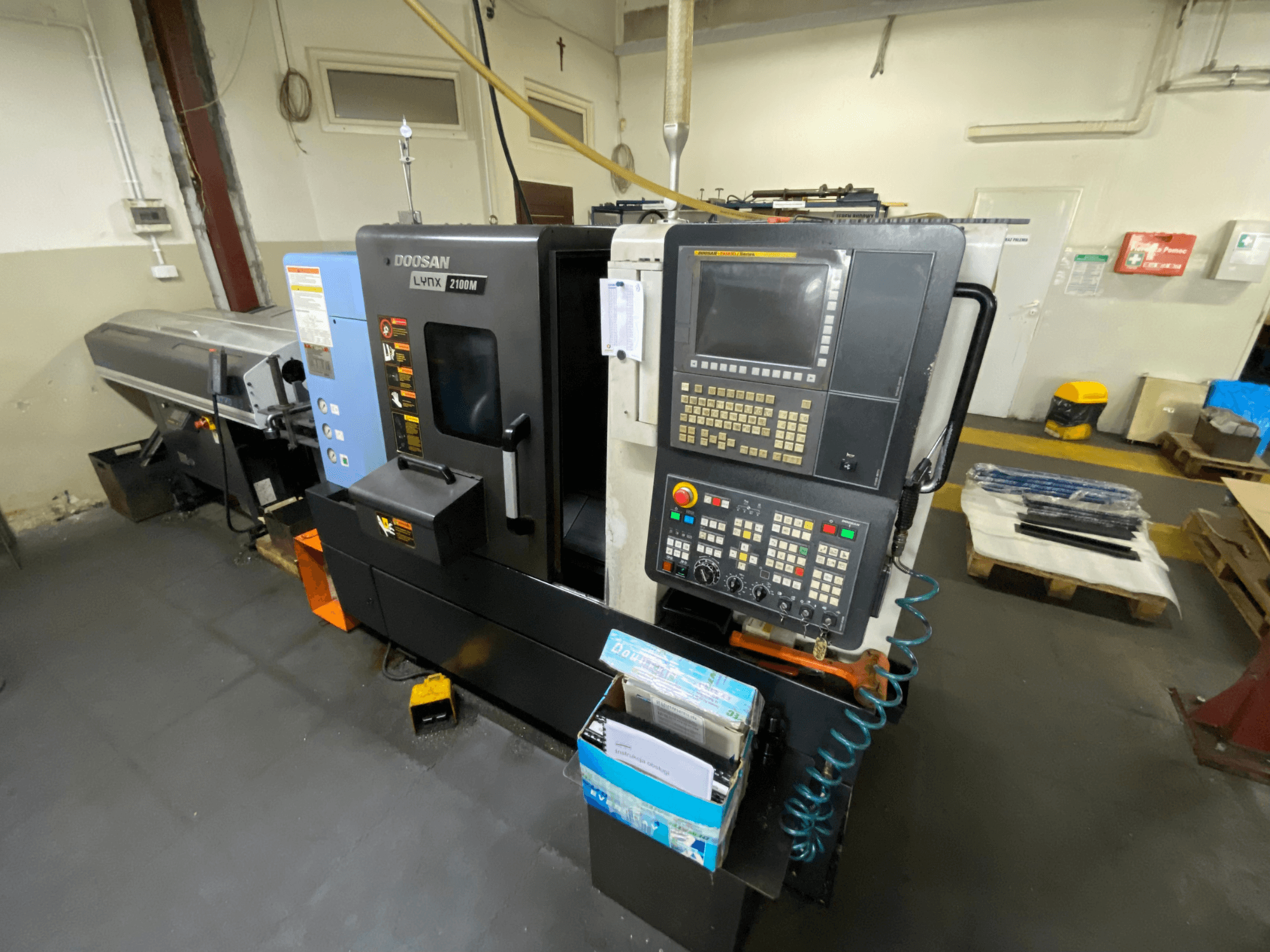 Die Horizontal-Drehmaschine DOOSAN LYNX 2100MA in Seitenansicht, mit Bedienfeld, Werkzeugen und Arbeitsbereich.