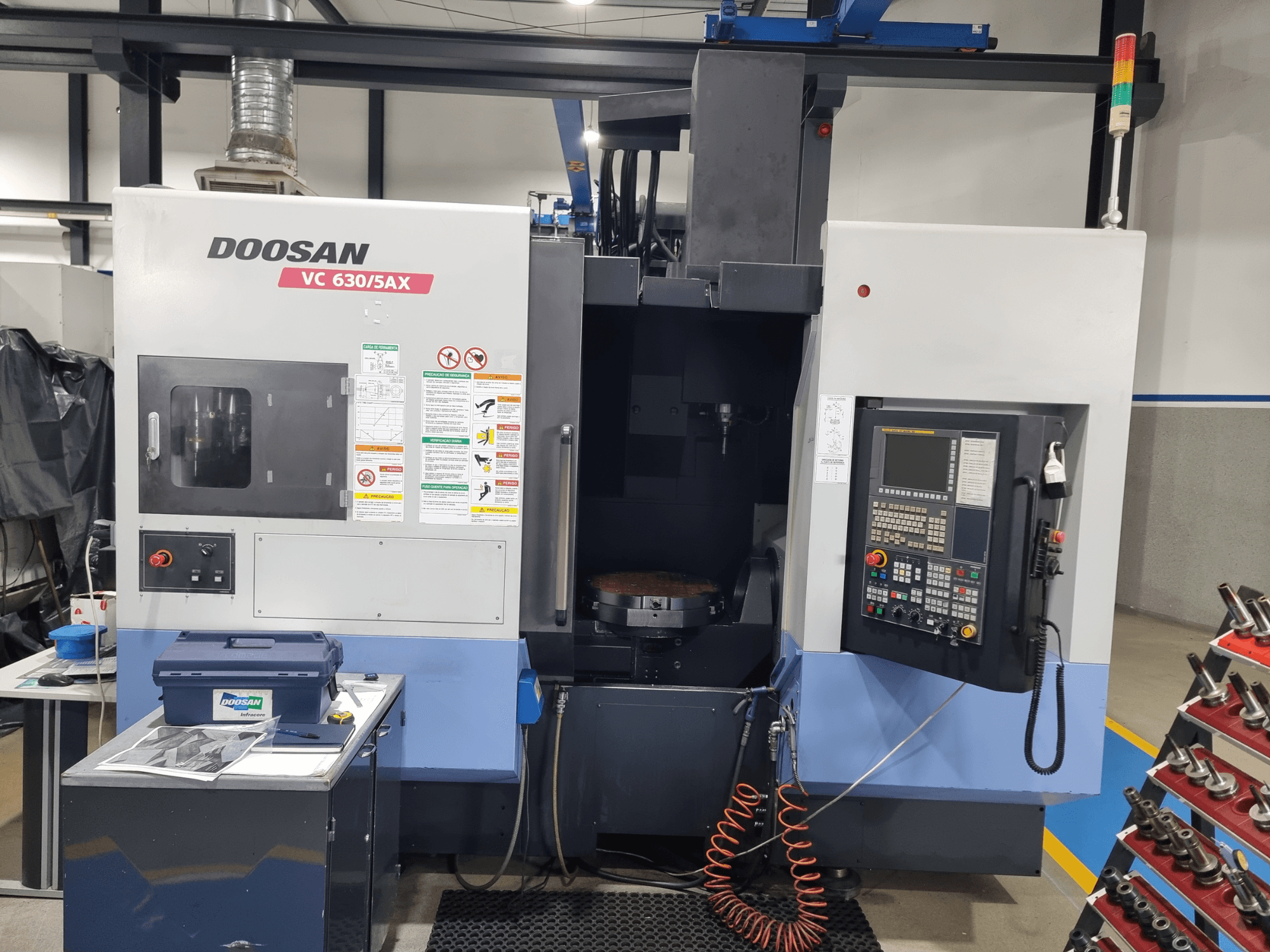 Universelles Bearbeitungszentrum DOOSAN VC 630/5AX, Vorderansicht mit Bedienfeld, Bearbeitungsbereich und Sicherheitsvorrichtungen.