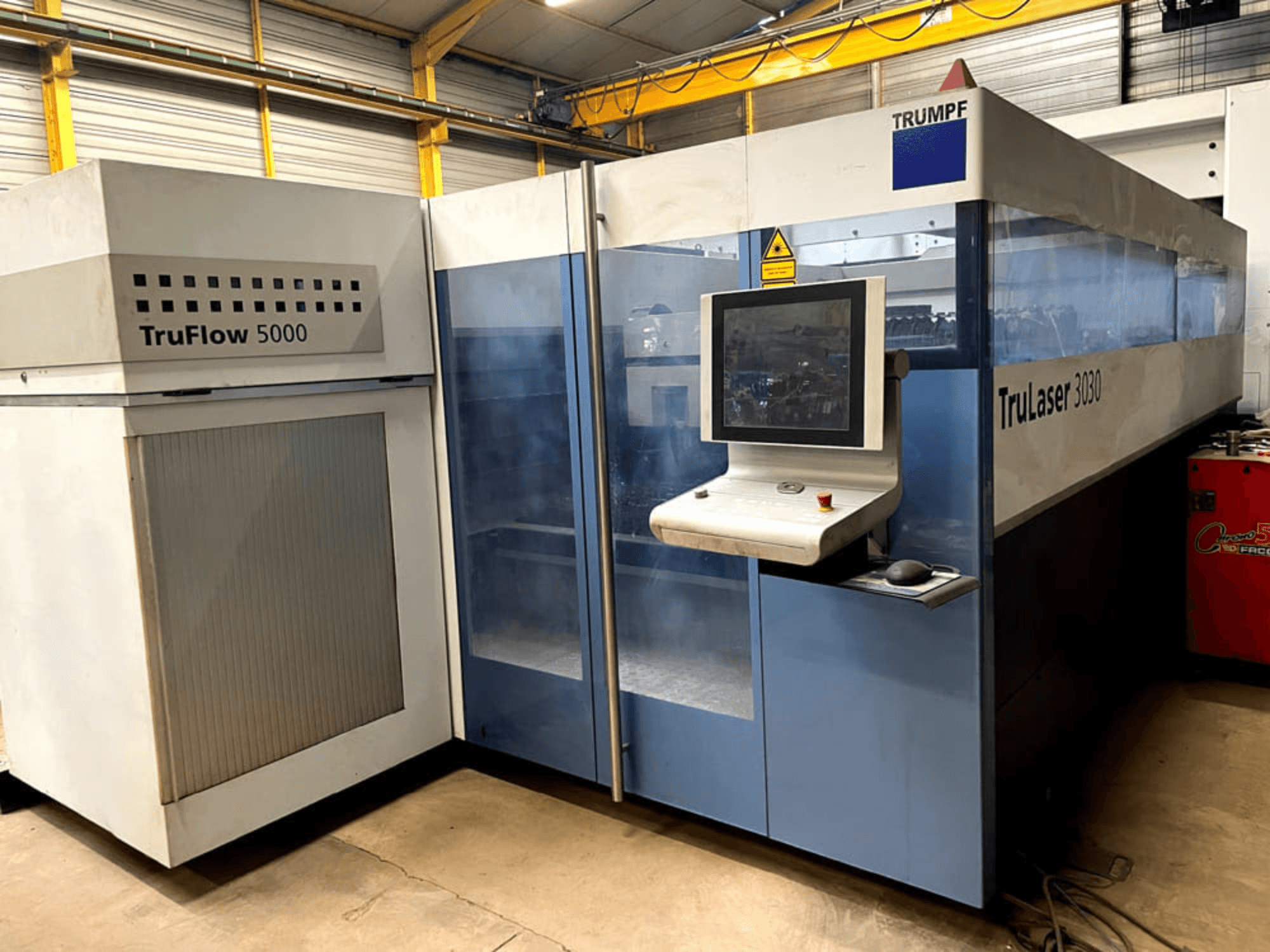 TRUMPF TruLaser 3030 CO₂-Laserschneidanlage in Frontansicht, mit Bedienfeld und angrenzendem TruFlow 5000-Gerät.