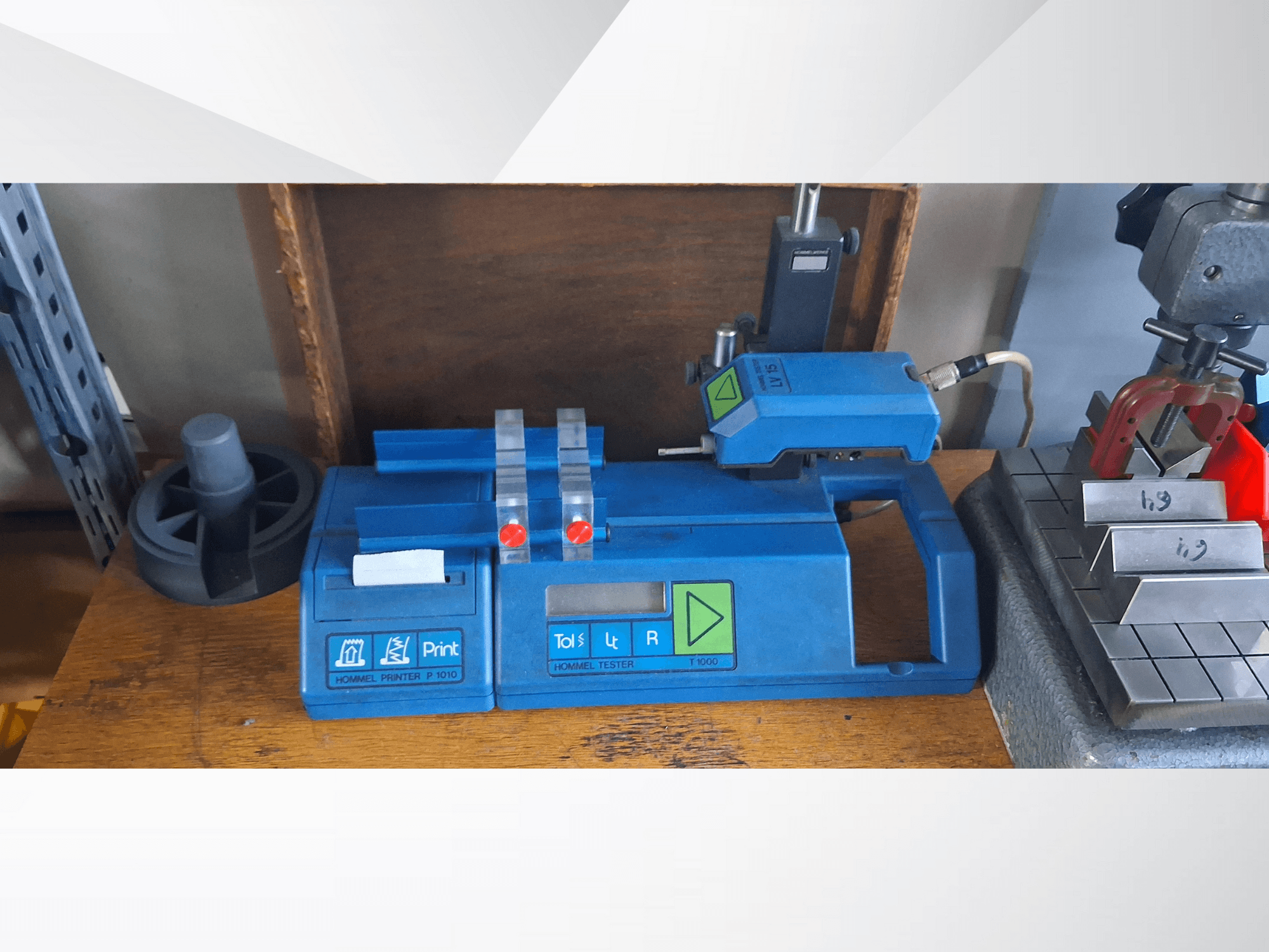 Hommel Drucker P 1010 und Tester T1000 in der Seitenansicht mit blauem Gehäuse, Tasten und roten Anzeigen auf einer Werkbank.