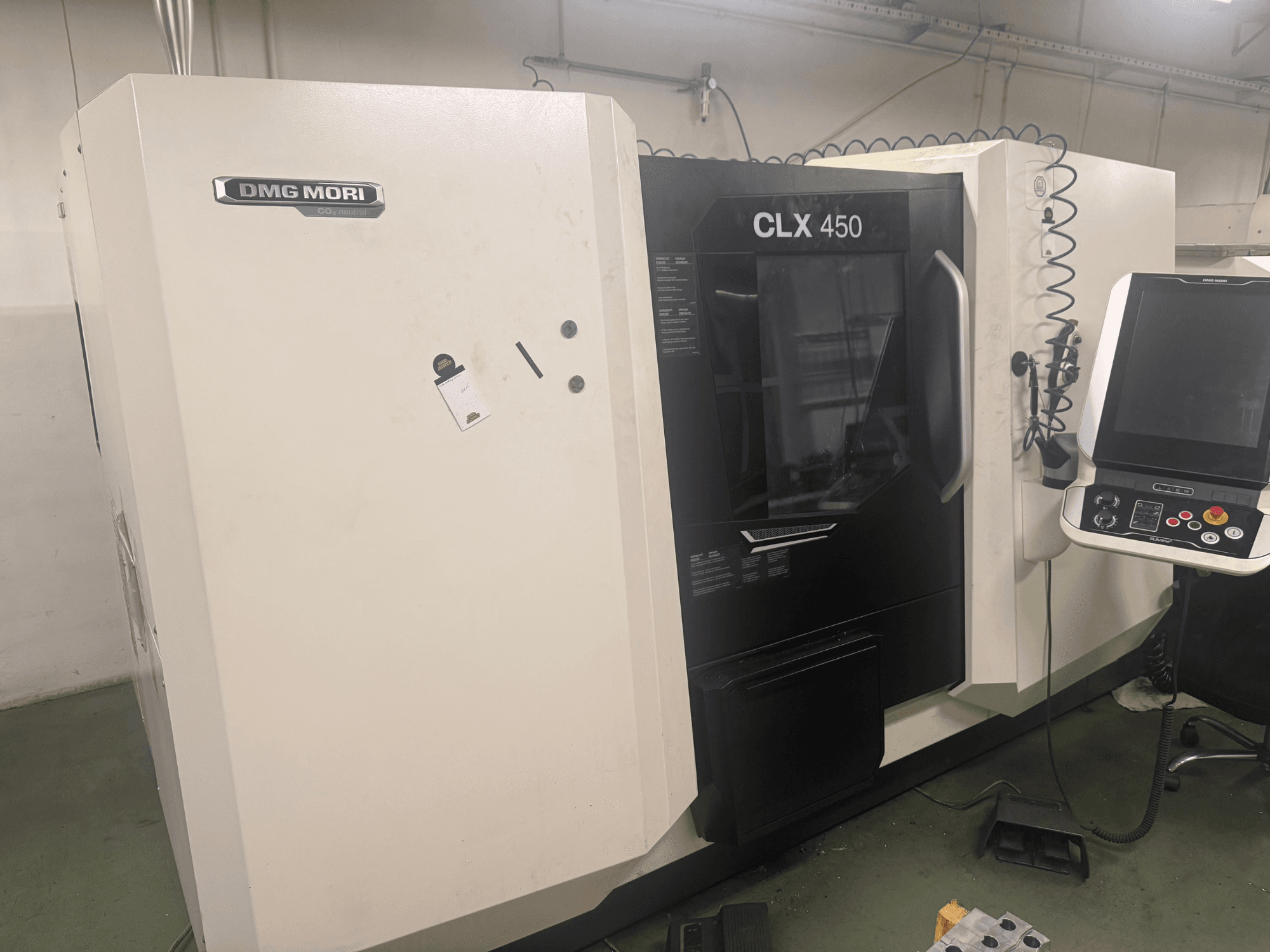 DMG MORI CLX 450 CNC-Maschine, Seitenansicht mit Bedienfeld, sichtbaren Bedientasten und sauberem Arbeitsbereich.