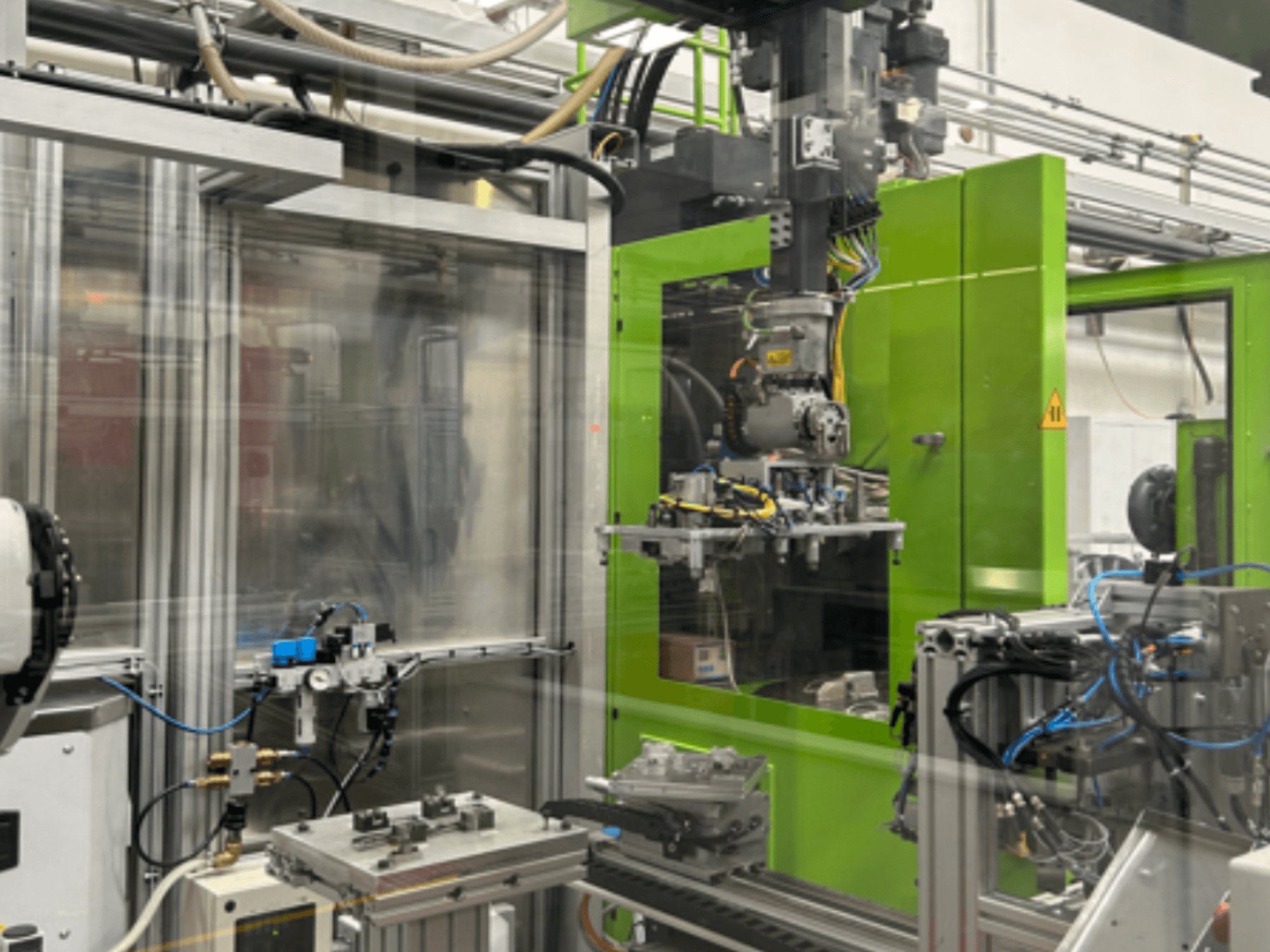 Industrieroboter in grünem Gehäuse mit mechanischen Komponenten und Rohrleitungen, von vorne gesehen.