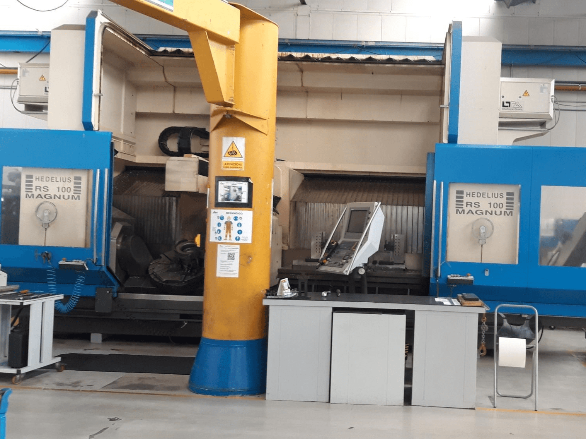 HEDALIUS RS 100 MAGNUM Maschine, Vorderansicht; mit Bedienfeld und gelber Säule in einem industriellen Arbeitsbereich.