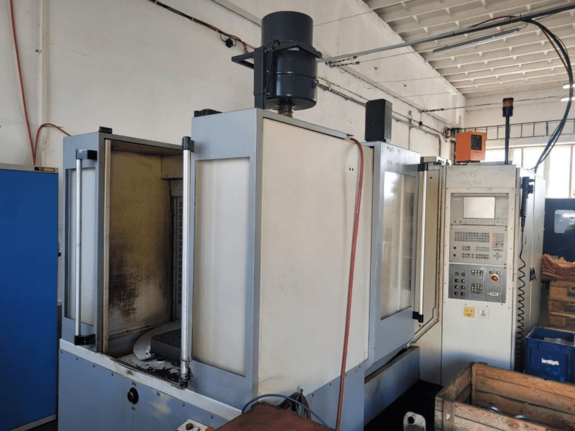 Industrielle CNC-Fräsmaschine mit Bedienpult, Seitenansicht, zeigt Gehäuse und sichtbare Verschmutzung der Oberflächen.