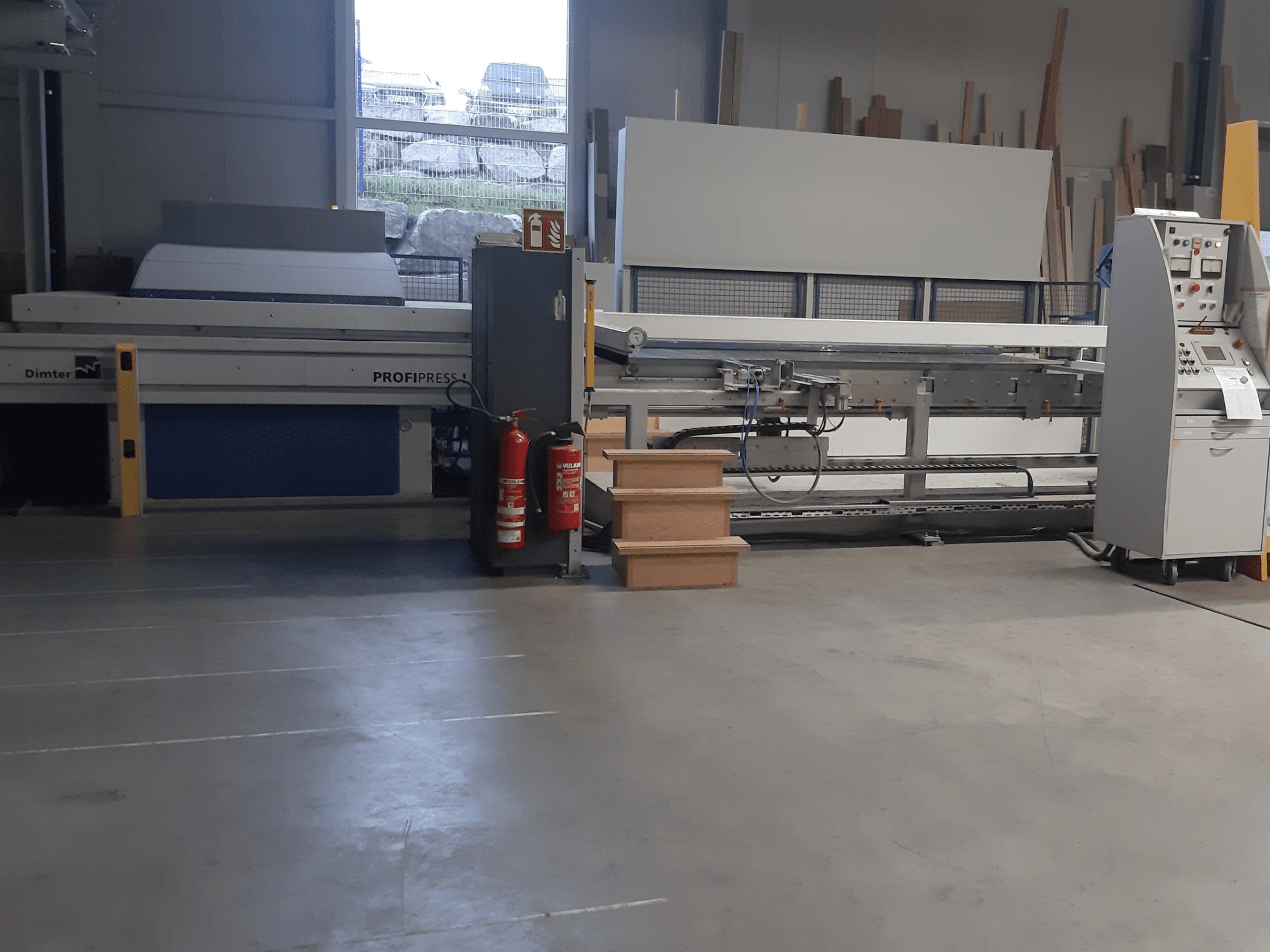 Dimter ProfiPress Maschine in einer Werkstatt, von vorne gesehen, mit Bedienfeld und Feuerlöschern in der Nähe.