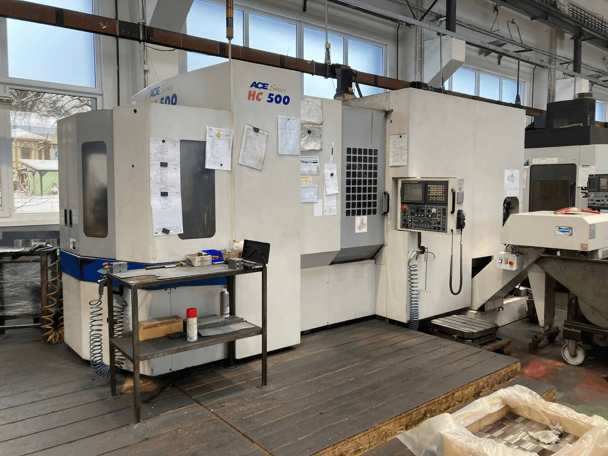 DOOSAN ACE HC-500 Horizontal-Bearbeitungszentrum, Vorderansicht; mit Bedienfeld, Mehrfach-Werkzeugspeicher und Industrieumgebung.