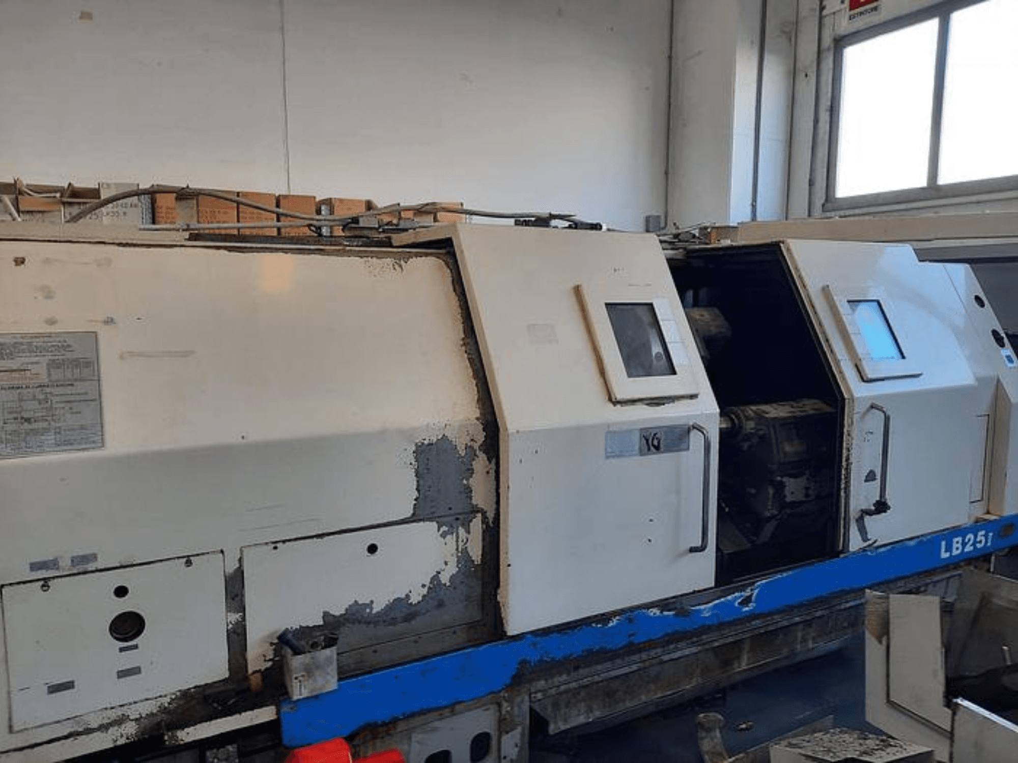 Gebrauchte LB251-Drehmaschine, Seitenansicht mit abgenutztem Äußeren, offenes Paneel mit Blick auf den Innenmechanismus und die Bedienelemente.