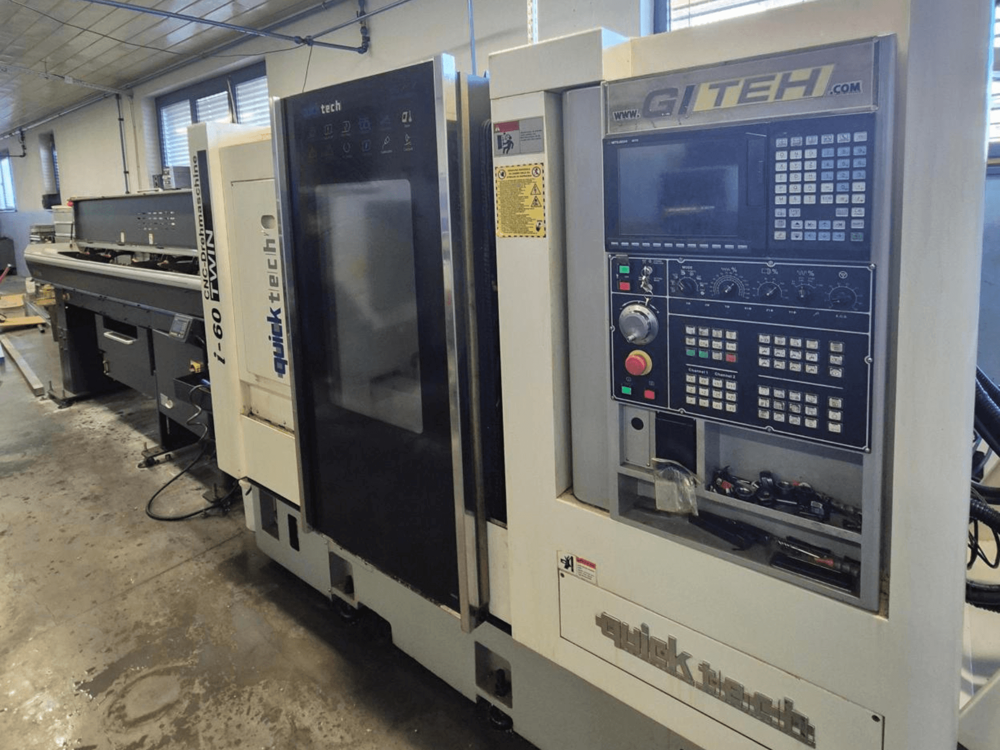 Quick Tech i-60 twin CNC-Maschine, Vorderansicht, mit GITEH-Bedienfeld und Bedientasten, in einer Werkstattumgebung.