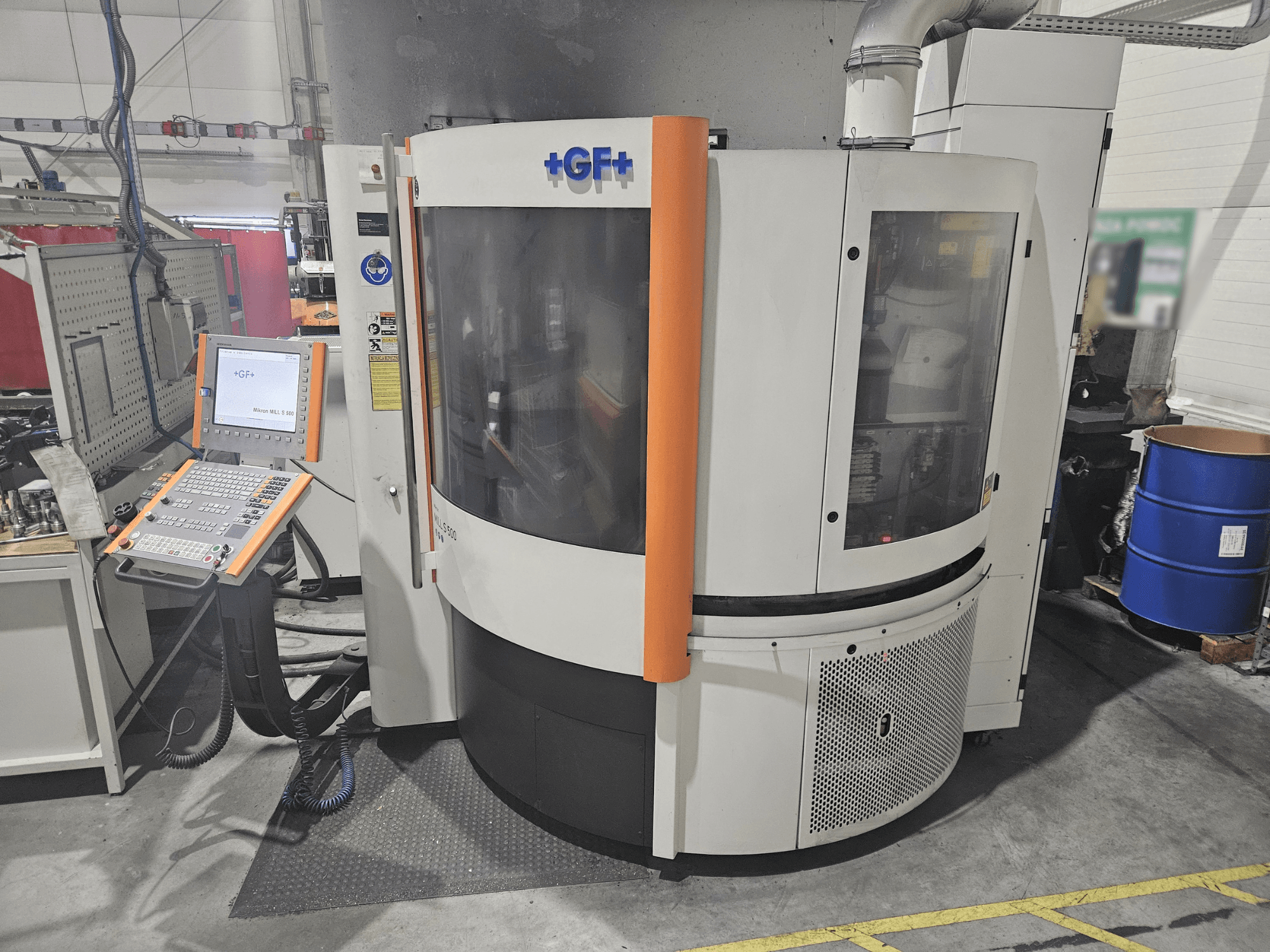 Werkzeugmaschine von GF Machining Solutions mit Bedienfeld, Vorderansicht; mit transparentem Bedienfeld, orangefarbenen Akzenten und industriellen Einstellungen.