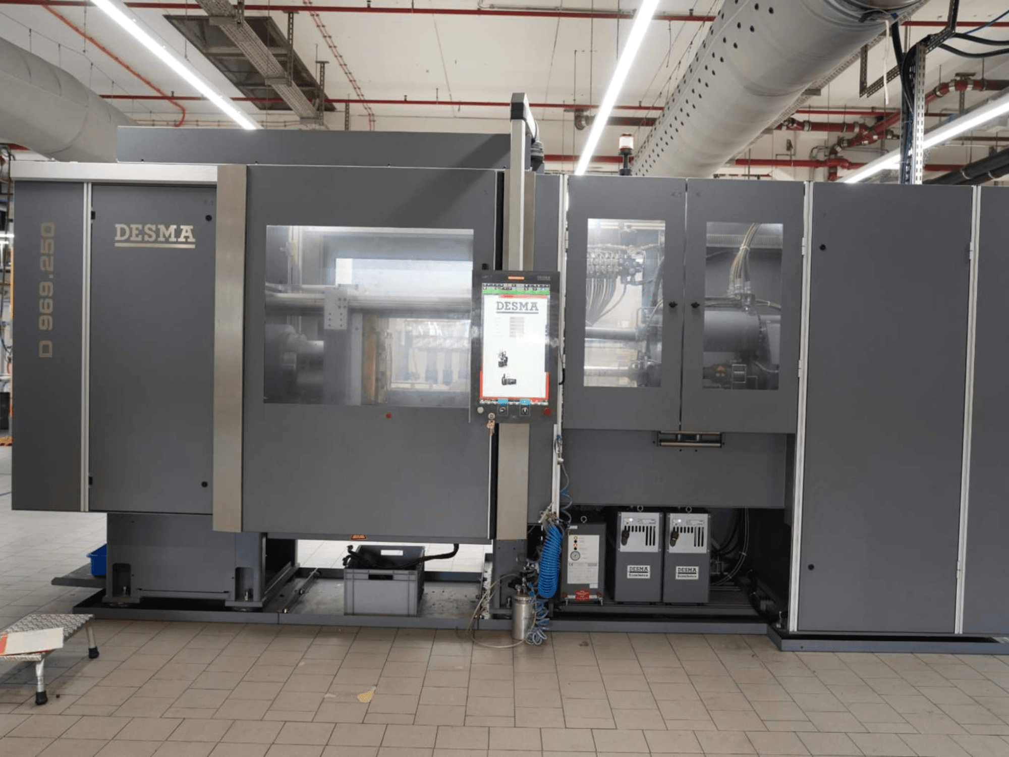 Vertikale Spritzgießmaschine Kloeckner Desma D 969.250 Z (S3) in einer Fabrikumgebung, Vorderansicht mit Bedienfeld.