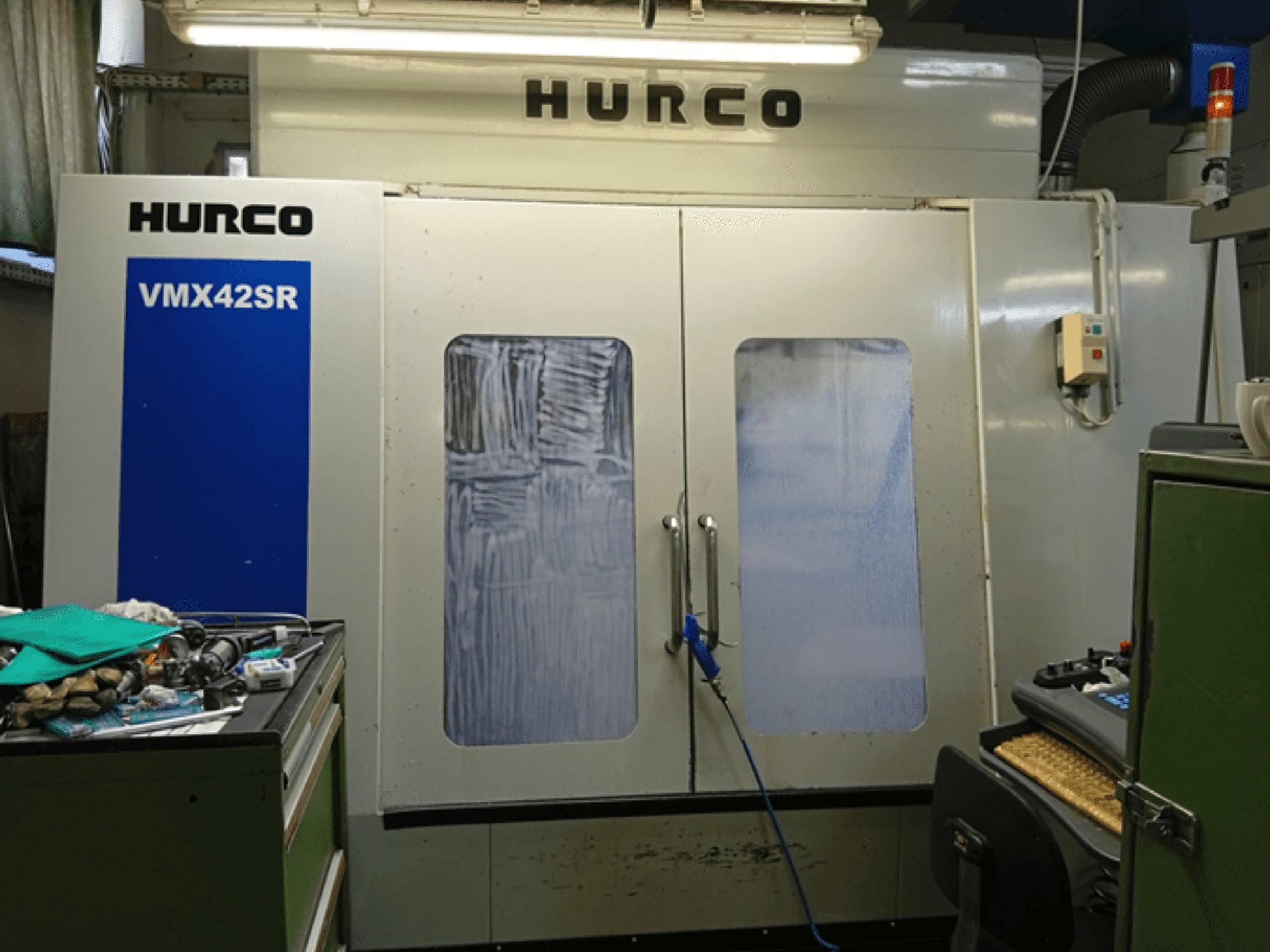 Hurco VMX 42SR Vertikal-Bearbeitungszentrum in der Vorderansicht, mit blauem Bedienfeld, Steuerungsschnittstelle und sauberem Arbeitsbereich.