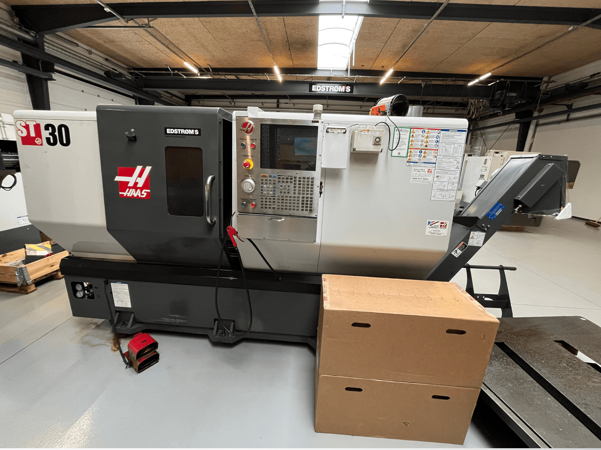 Haas ST-30 CNC-Drehmaschine von der Seite gesehen, mit Bedienfeld, Modellplakette und zwei Kartons in der Nähe.