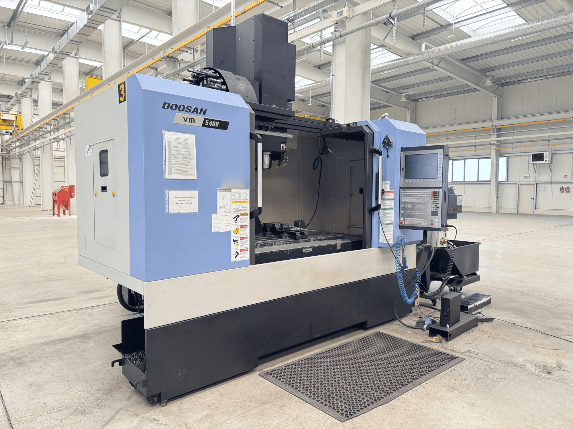 DOOSAN VM 5400 Vertikal-Bearbeitungszentrum, Frontansicht mit Bedienfeld und Arbeitsbereich in einer großzügigen Industrieumgebung.