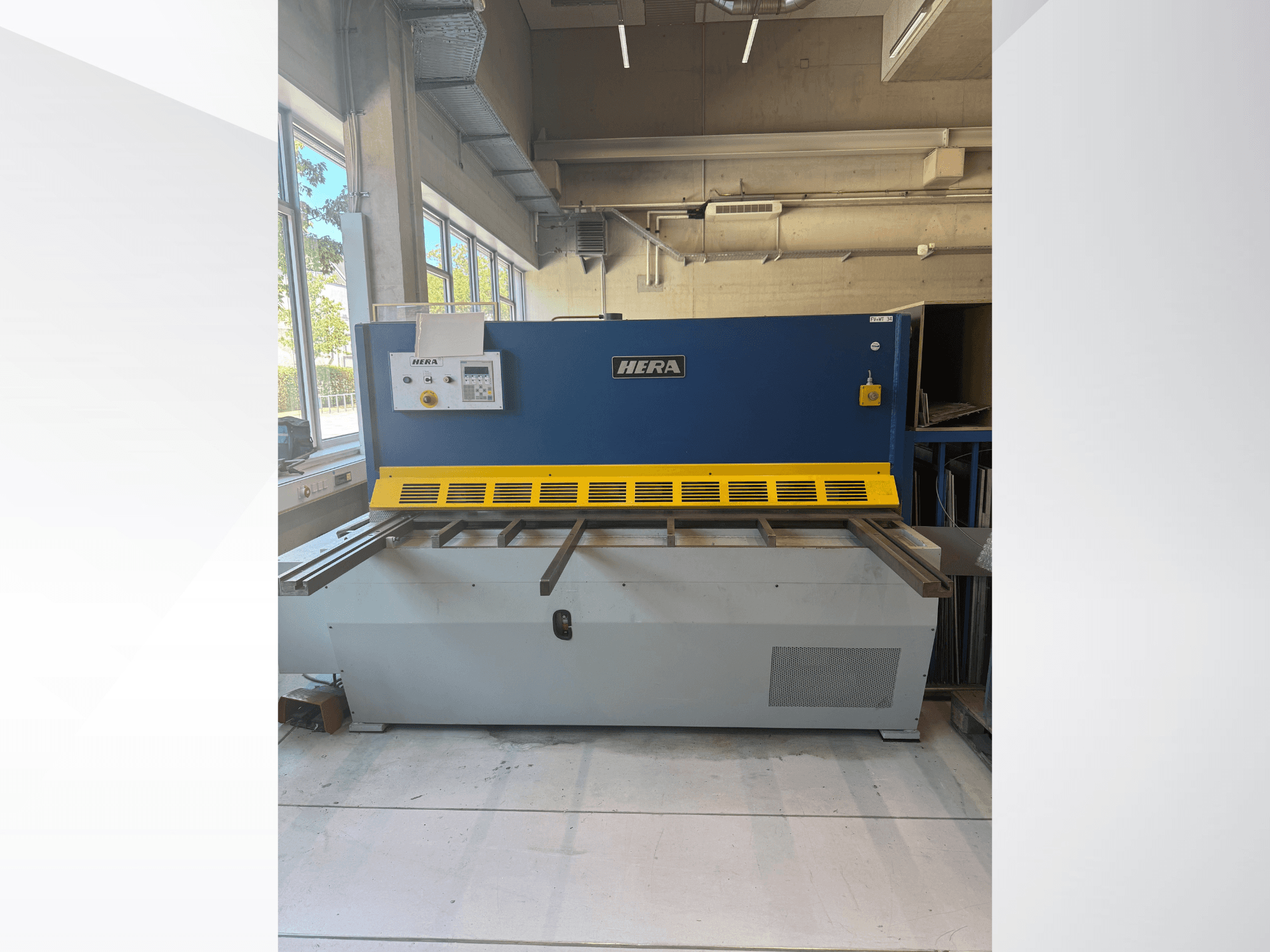 Hydraulische Schere HERA TS 2000x6 in Frontansicht, in blau-gelber Farbgebung, mit Bedienfeld und Schneidetisch.