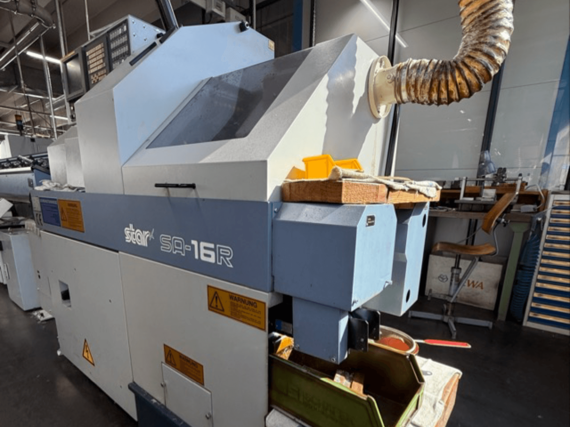 Stark SA-16R Maschine von vorne gesehen, mit einem konischen Auspuff und einem Arbeitsbereich mit gelben Werkzeugen und Warnschildern.