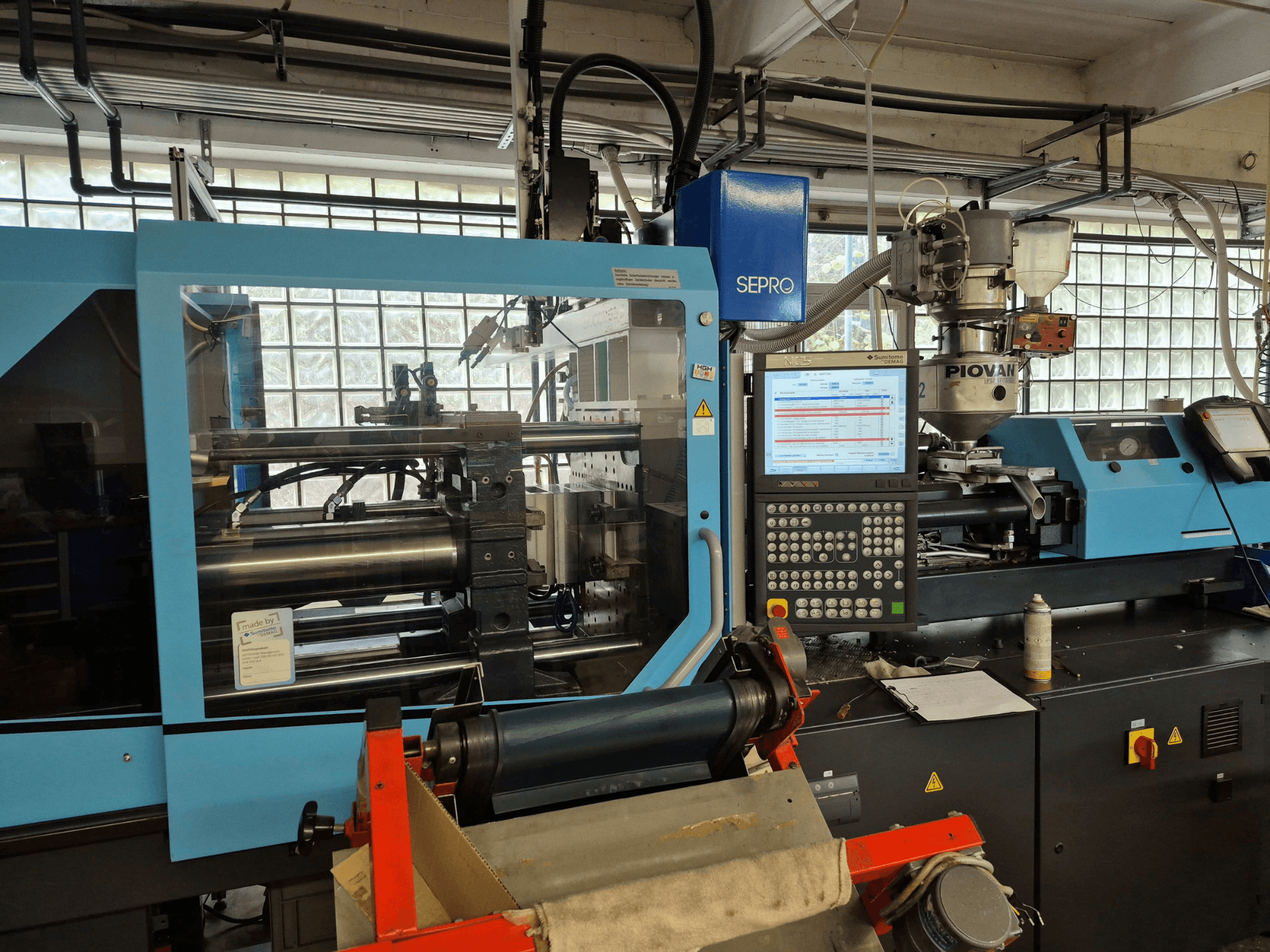 Hydraulische Spritzgießmaschine SUMITOMO SHI DEMAG Systec 120/470-430, Vorderansicht mit sichtbarem Bedienfeld und Zuführsystem.