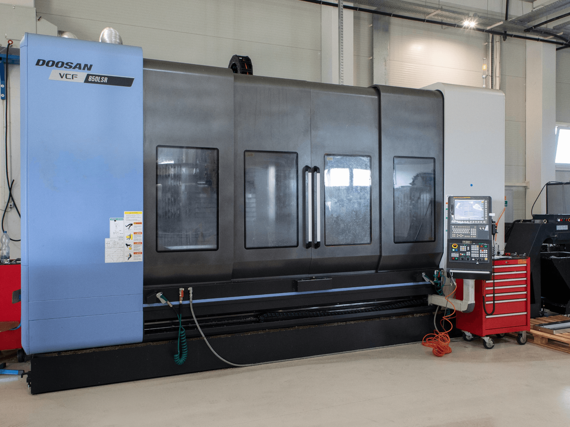 DOOSAN VCF850 Fräs-Dreh-Zentrum, Vorderansicht; mit großen Doppelfenstern, Bedienfeld und Werkzeugaufbewahrung. Ideal für die Zerspanung.