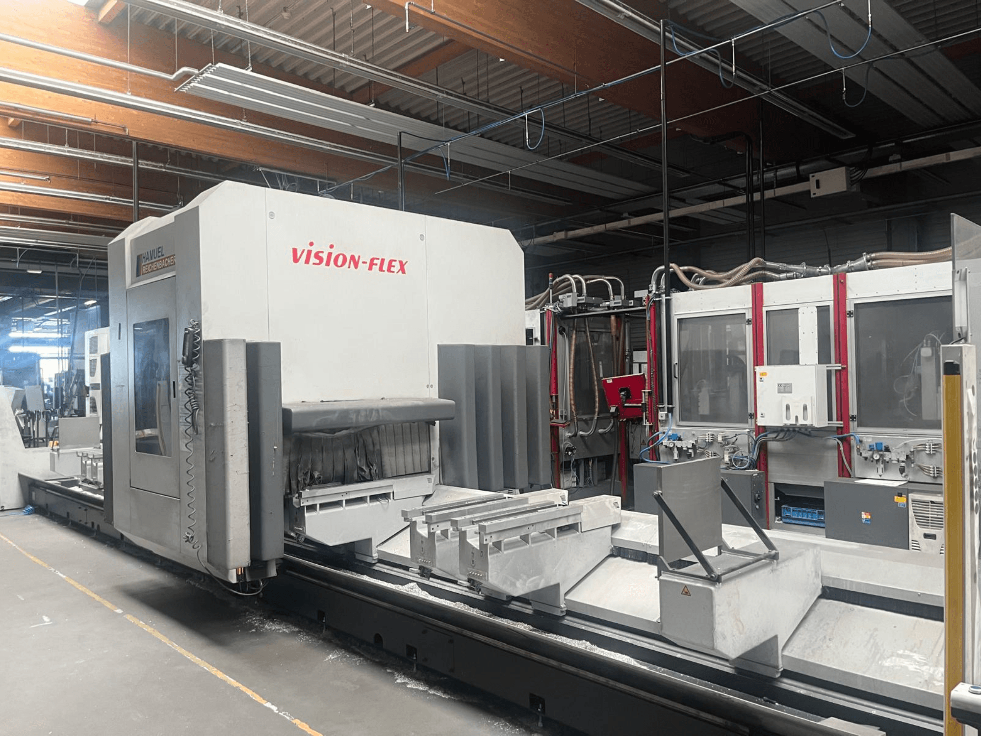 Vertikales Bearbeitungszentrum „Hamuel Reichenbacher Vision Flex“, Seitenansicht mit Arbeitsbereich und Bedienelementen in einer industriellen Umgebung.