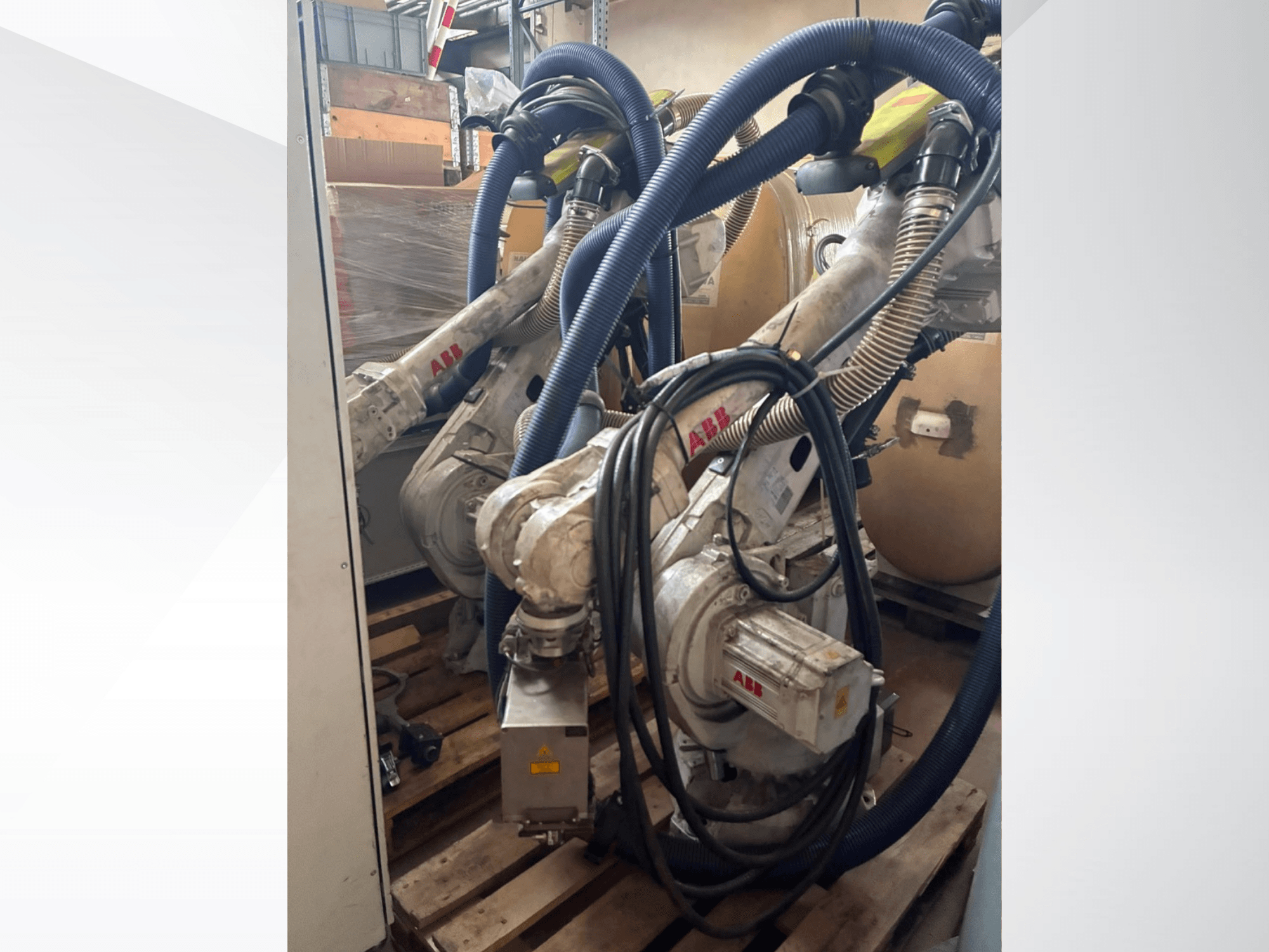 ABB IRB 4600-40/2,55-Roboterarm, Seitenansicht mit zwei Armen und angeschlossenen Schläuchen, montiert auf Paletten in einer Lagerumgebung.
