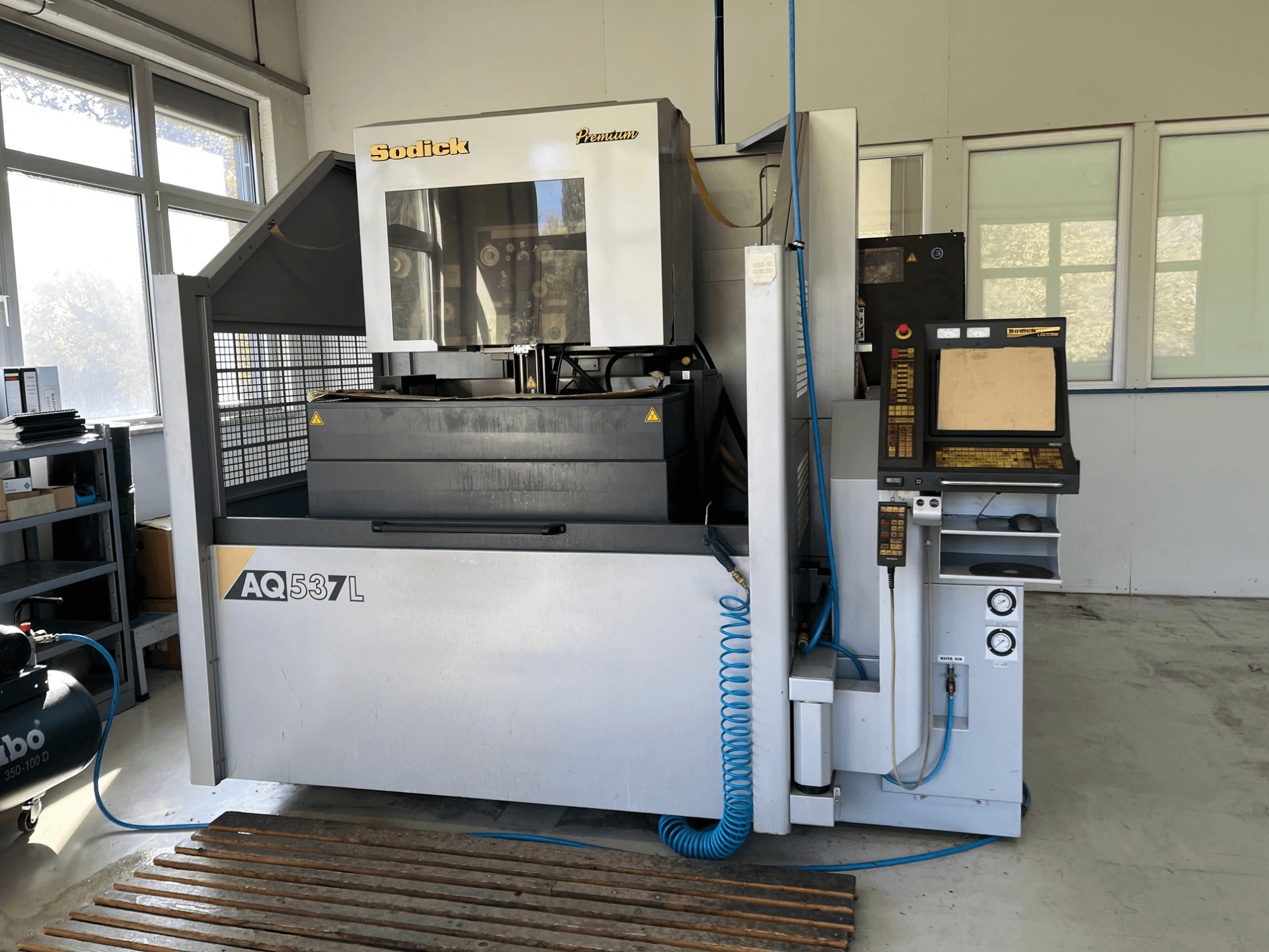 Sodick AQ537L Funkenerosionsmaschine (EDM) in der Vorderansicht, mit Bedienfeld, Wasserkühlleitungen und Arbeitsbereich.