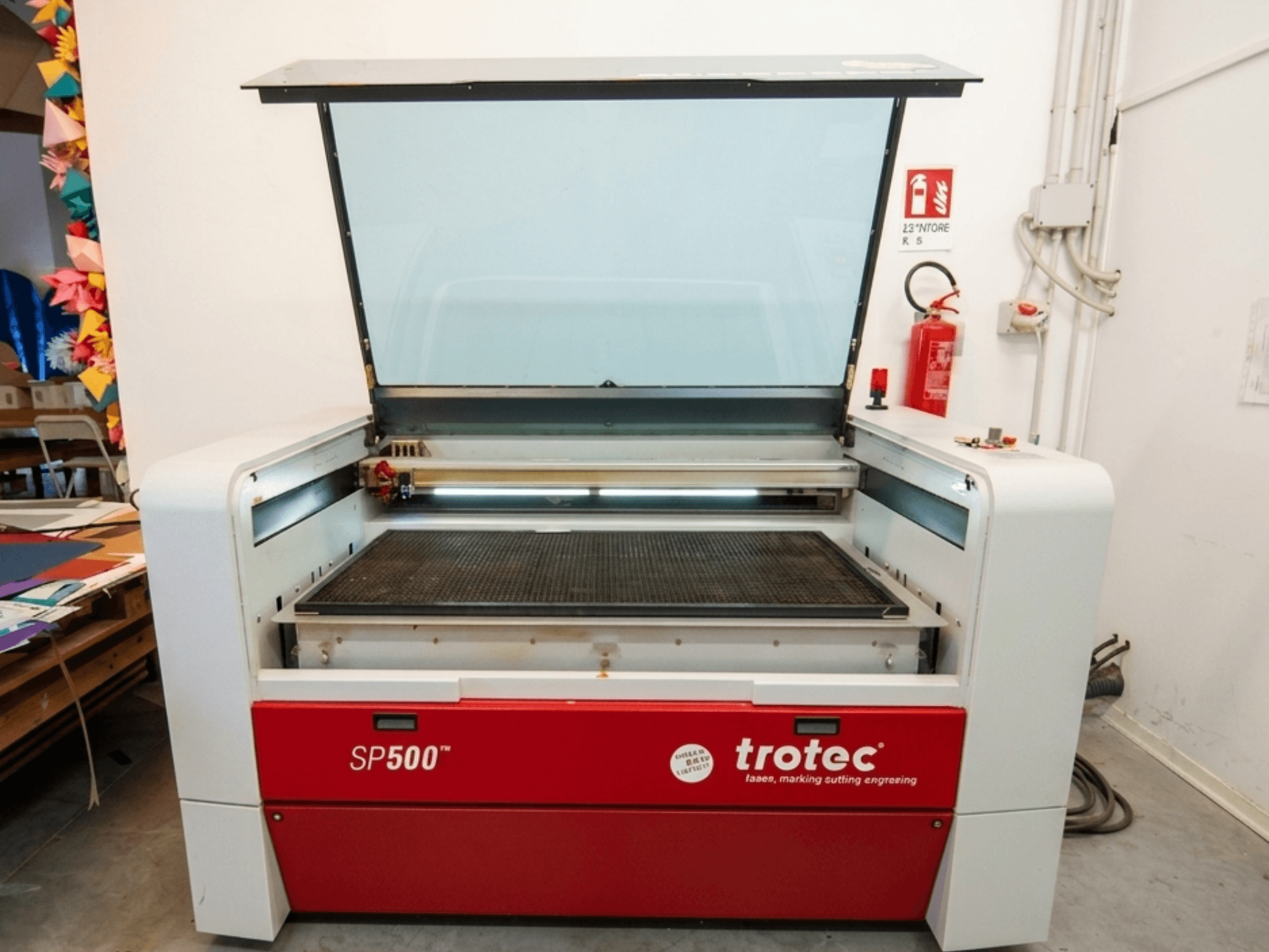 Trotec SP500 C200 Lasergraviermaschine in der Vorderansicht, mit geöffnetem Deckel, der den Arbeitsbereich und die Bedienelemente zeigt.