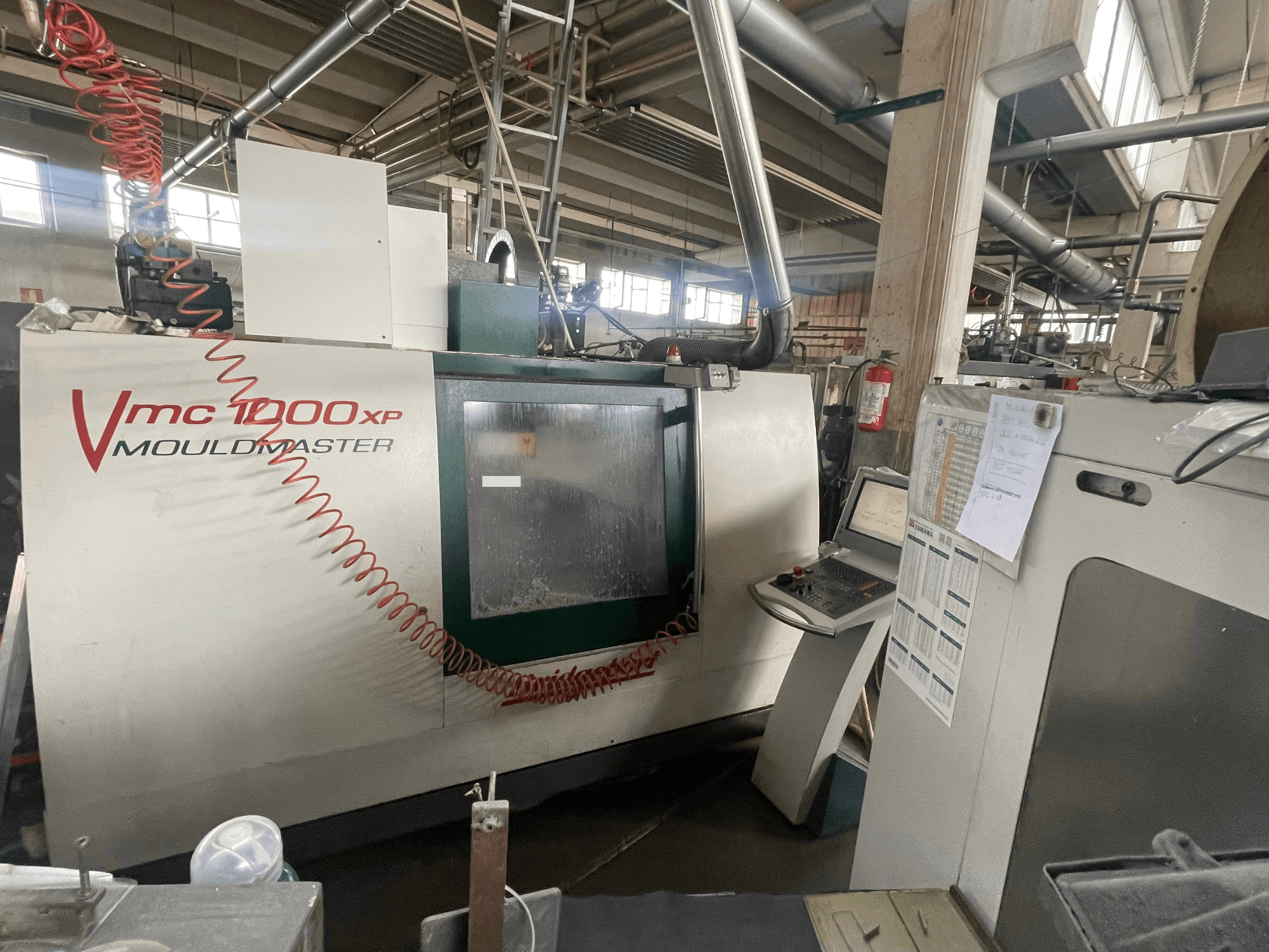 Vertikales Bearbeitungszentrum Bridgeport VMC 1000, Vorderansicht, mit Blick auf das Bedienfeld und Maschinendetails in einer industriellen Umgebung.
