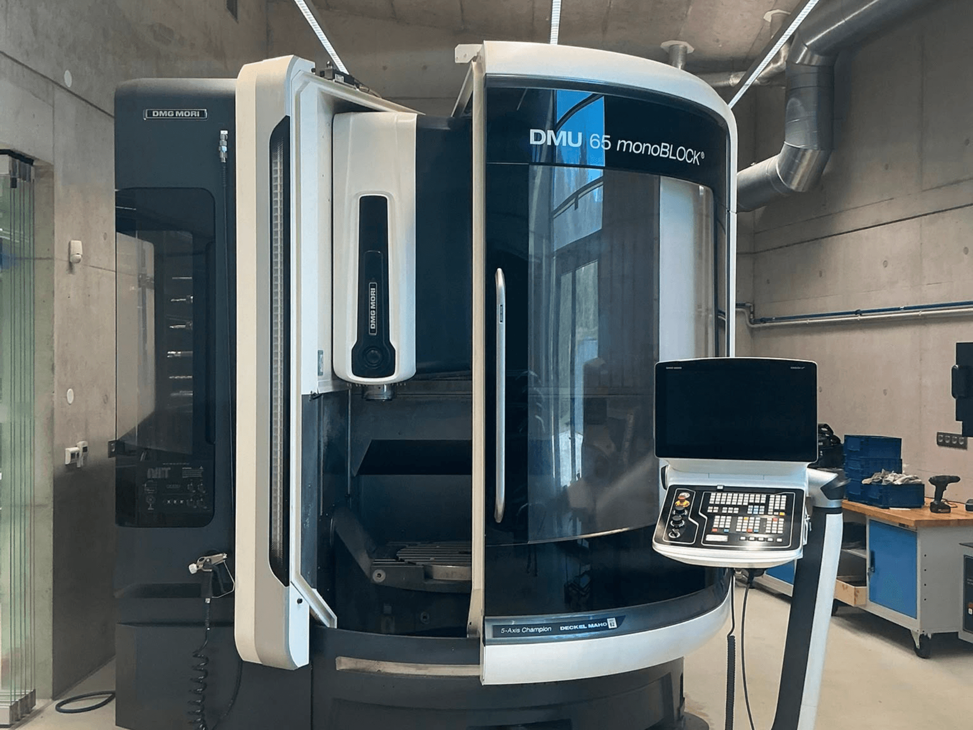 Vertikales Bearbeitungszentrum DMG MORI DMU 65 monoBLOCK, Vorderansicht, mit Darstellung des Bedienfelds und der Maschinendetails in einer Werkstattumgebung.