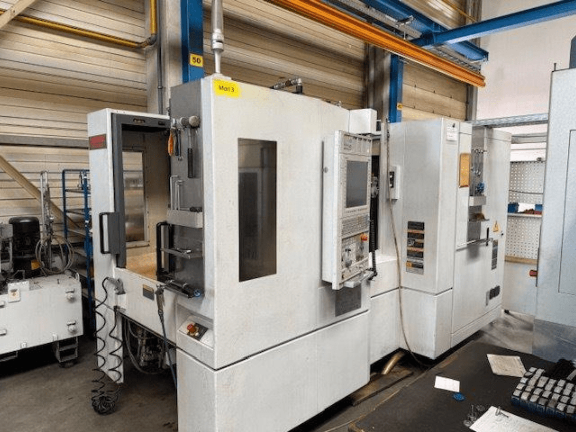 Frontansicht eines MORI SEIKI NH4000 DCG Horizontal-Bearbeitungszentrums mit geöffneter Tür und sichtbarem Bedienfeld, das den Arbeitsraum zeigt.