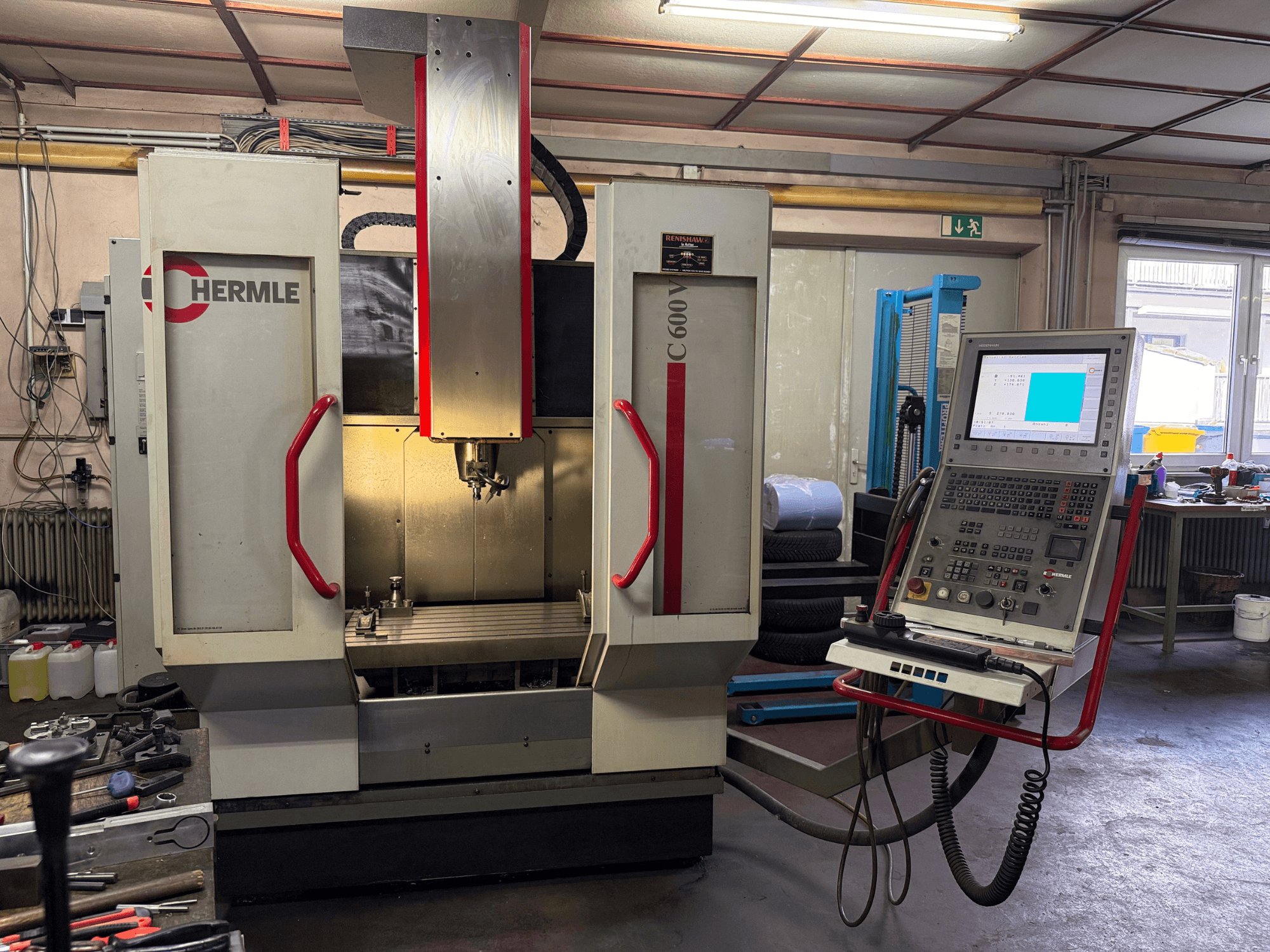 Hermle C 600 CNC-Fräsmaschine in der Frontansicht mit einem Bedienfeld mit zahlreichen Tasten und einem großzügigen Arbeitsraum.
