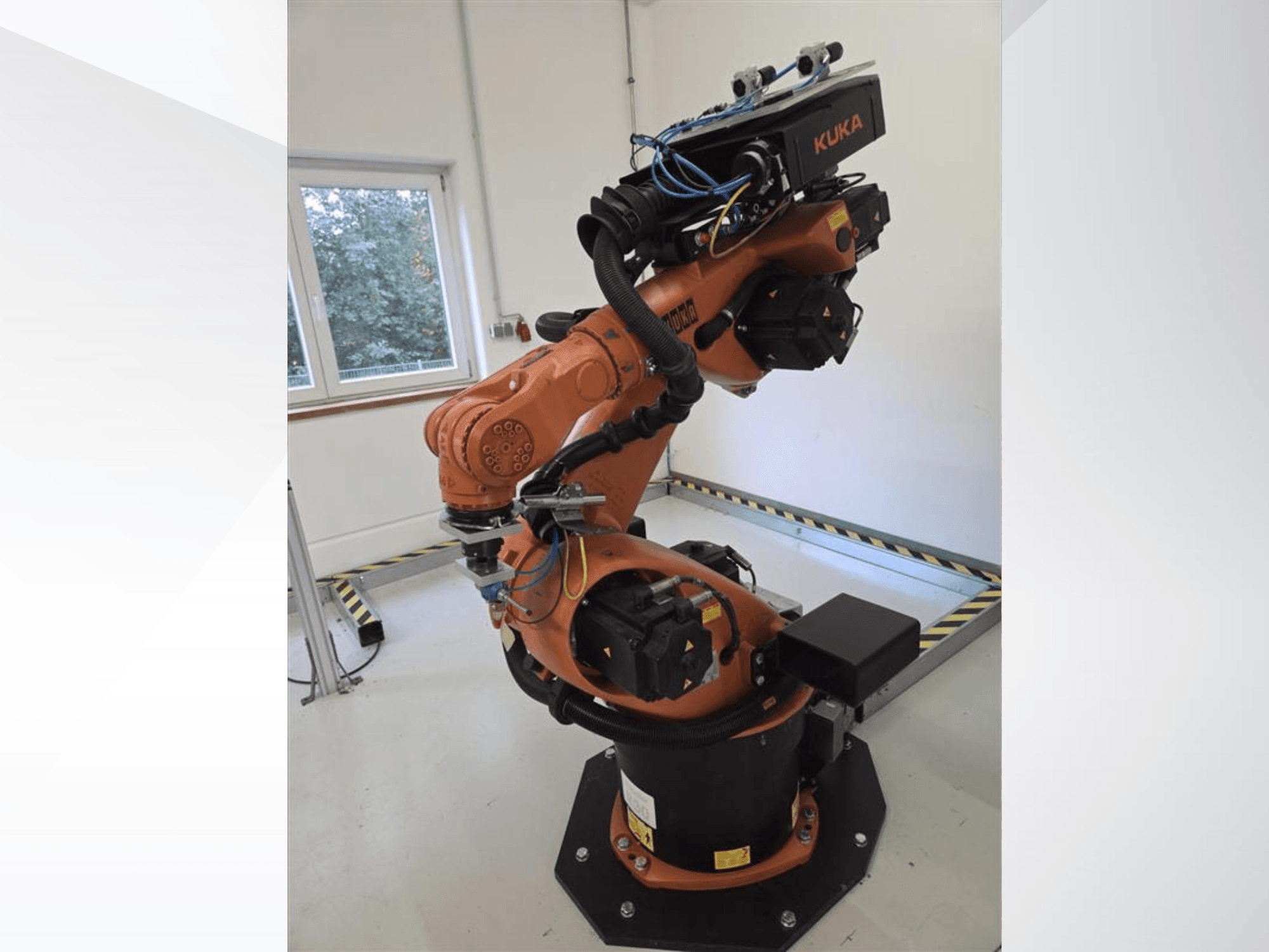 KUKA KR60 HA-Roboterarm in Seitenansicht, der die mechanischen Gelenke und die Verkabelung auf einem industriellen Sockel zeigt.