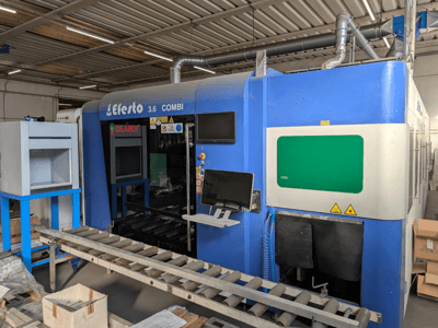 Faserlaserschneidemaschine EFESTO 3.6 COMBI, Seitenansicht, mit Bedienfeld und Sicherheitsanzeigen in blauer Ausführung.