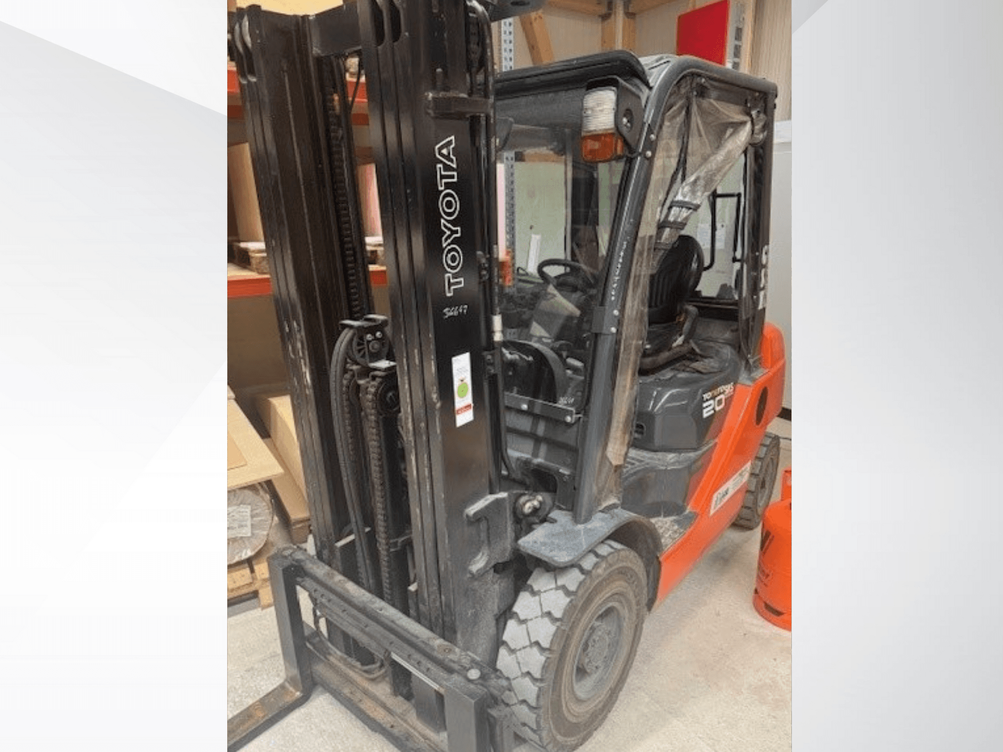 Toyota 20 Gabelstapler von vorne gesehen, mit schwarzem Mast, transparenter Kabine und orangefarbenem Propantank daneben.