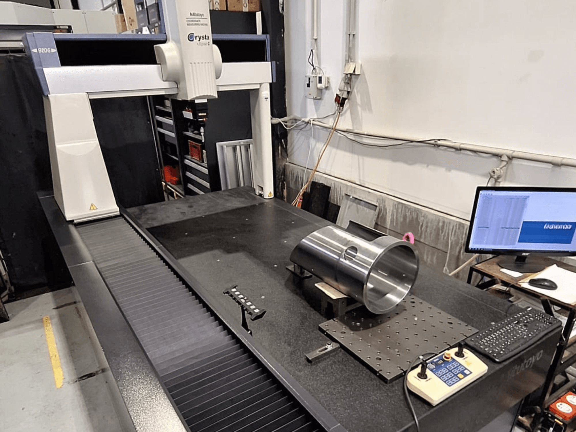 Mitutoyo Crysta-Apex C9206 KMG in Vorderansicht, Messung eines zylindrischen Metallteils auf einer schwarzen Granitplatte.
