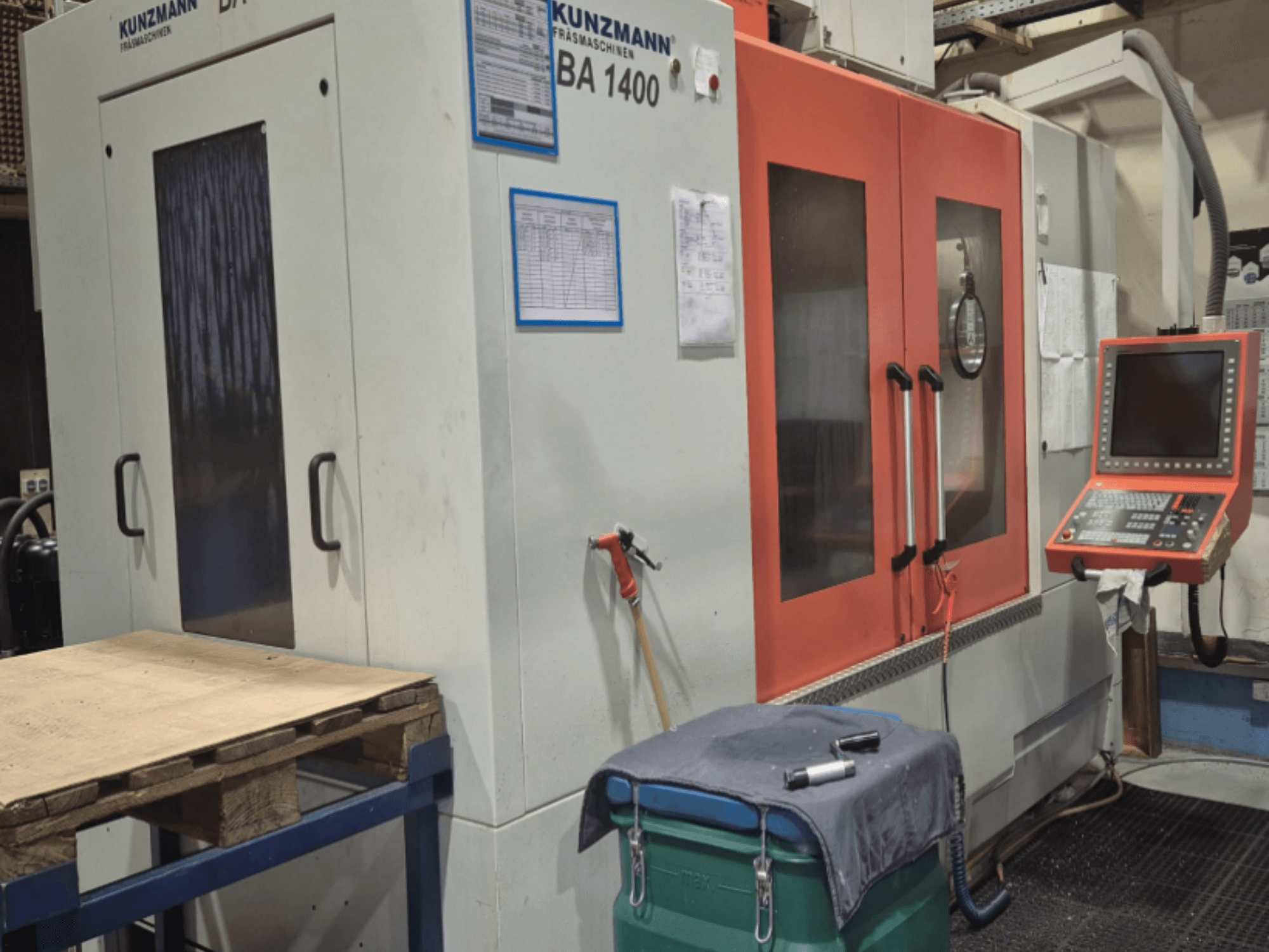 KUNZMANN BA1400 Vertikal-Bearbeitungszentrum in der Frontansicht, mit orangefarbenen Türen, Bedienfeld und Arbeitstisch.