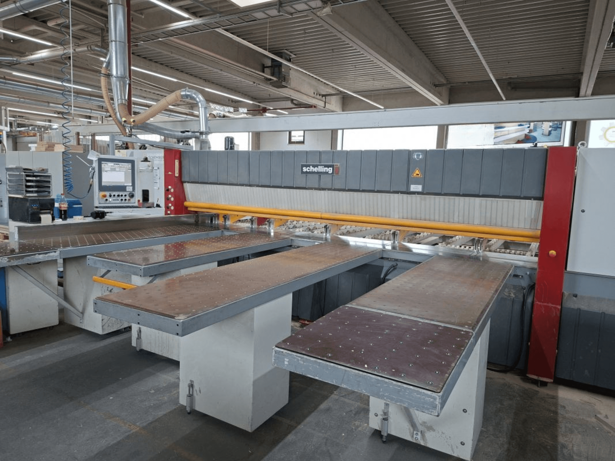 Plattensäge SCHELLING FH 4 in der Werkstatt, mit zwei ausgefahrenen Tischen und Bedienpult. Frontansicht, die die Betriebseinrichtung zeigt.