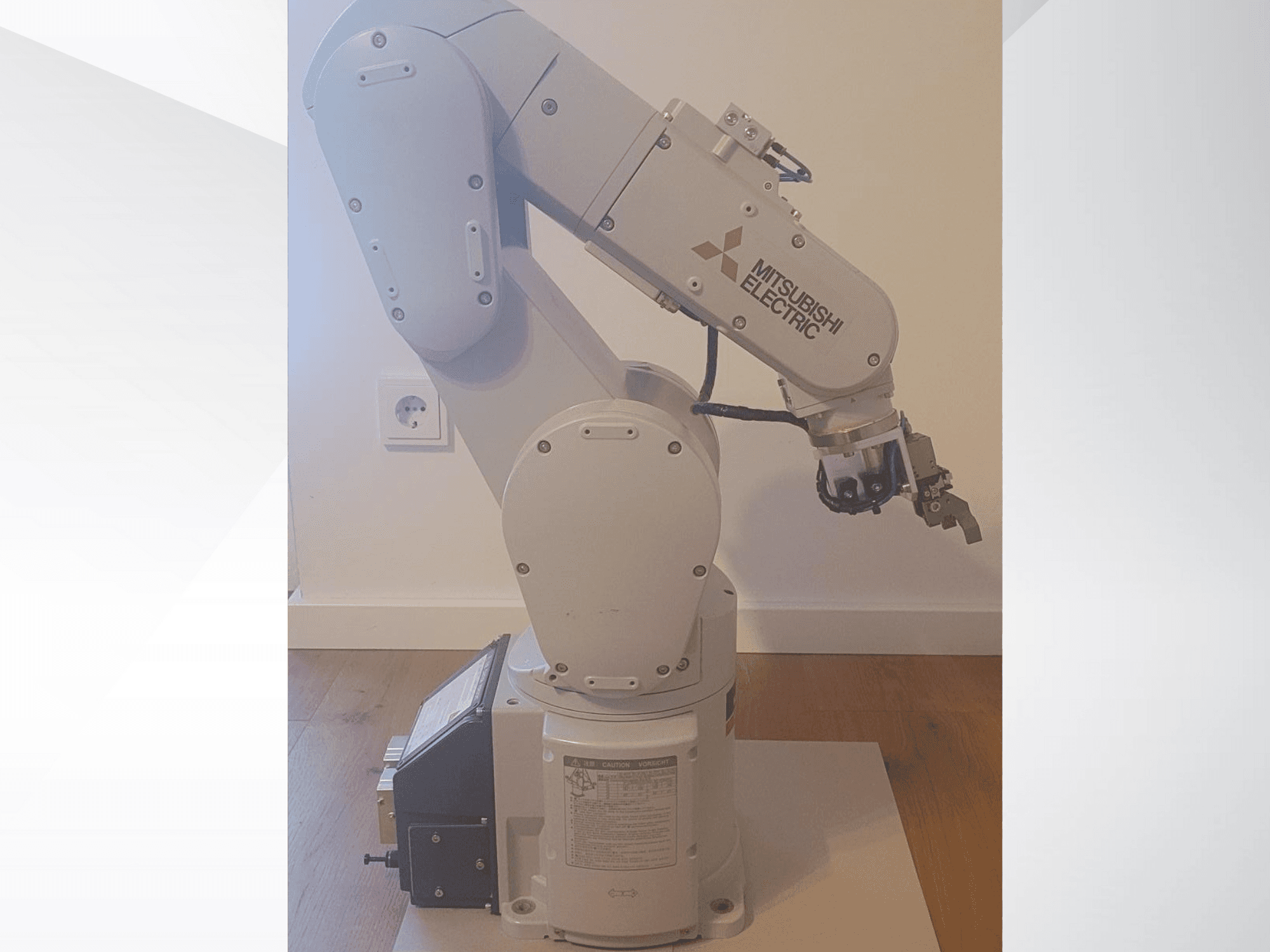 Mitsubishi Electric Roboterarm, Seitenansicht, mit einem Greifer und einem detaillierten Bedienfeld an der Basis für die Betriebseinstellungen.