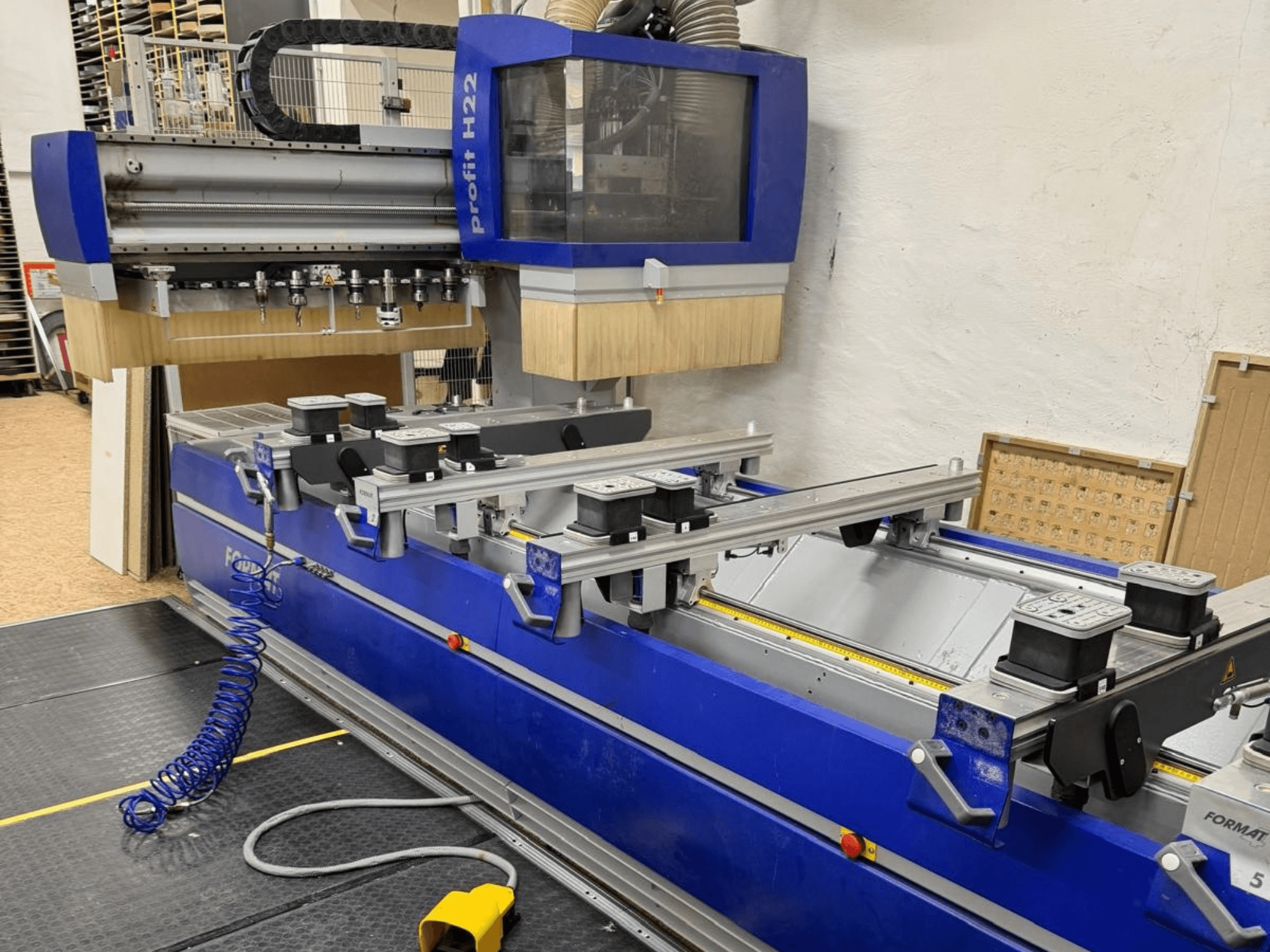 FORMAT4 PROFIT H22 CNC-Holzbearbeitungszentrum, Vorderansicht, mit sichtbaren Bearbeitungswerkzeugen und Spannvorrichtungen auf dem blauen Gehäuse.