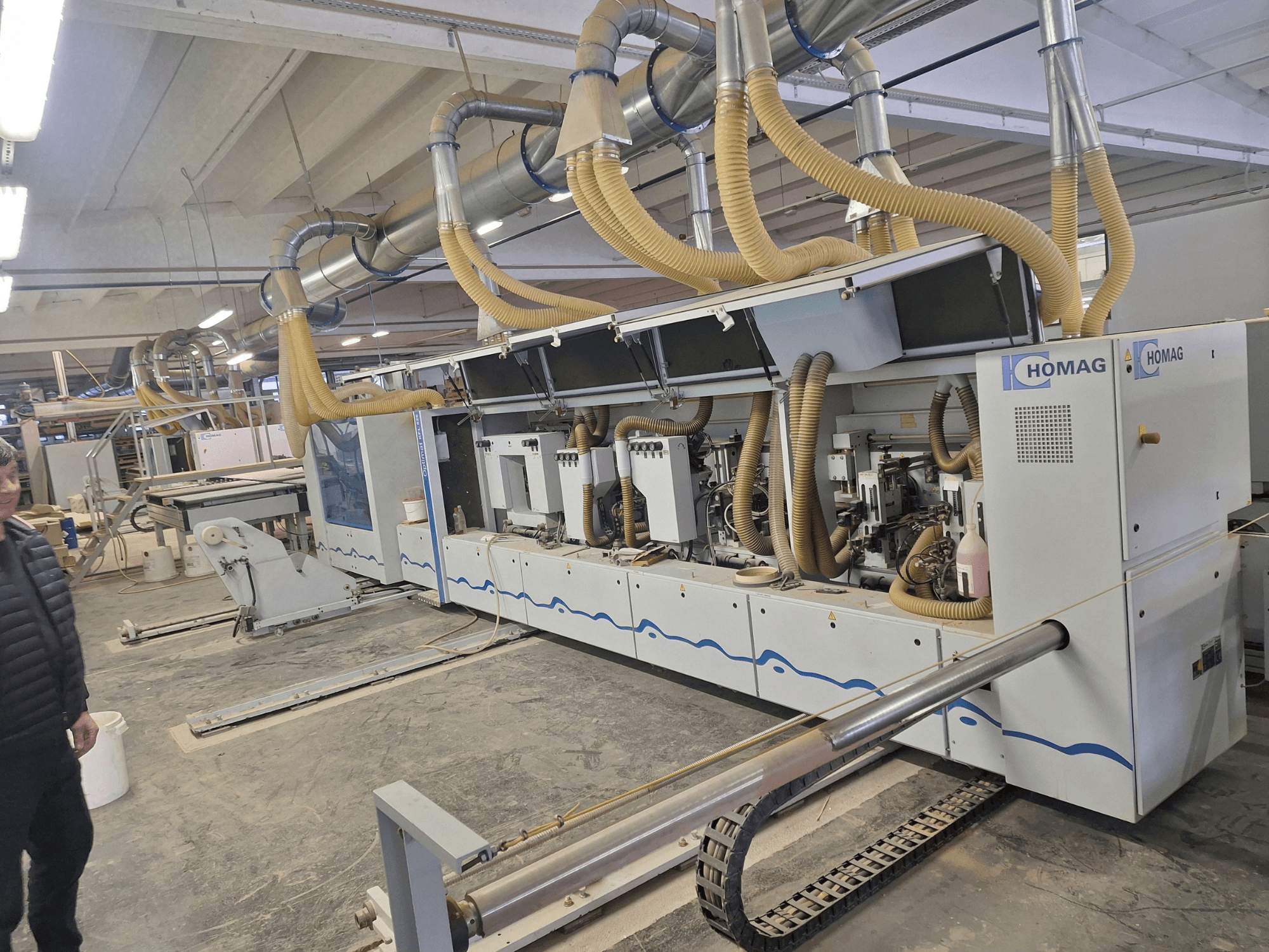 HOMAG Holzbearbeitungsmaschine in einer Fabrikumgebung, Vorderansicht mit mehreren Spindeln und Staubabsaugung.