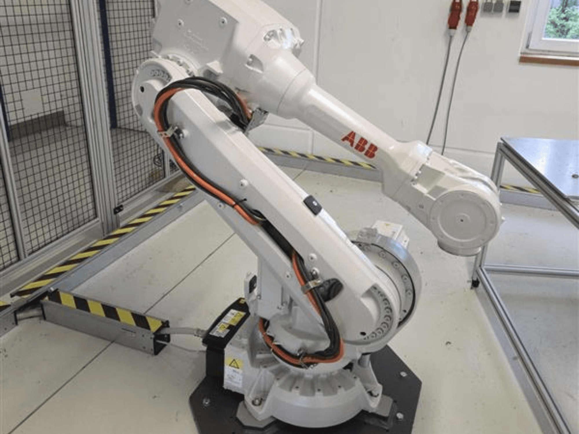 Der ABB IRB 4600-45/2.05-Roboterarm in der Seitenansicht, der seinen Gelenkaufbau und die an der Basis befestigten Kabel zeigt.