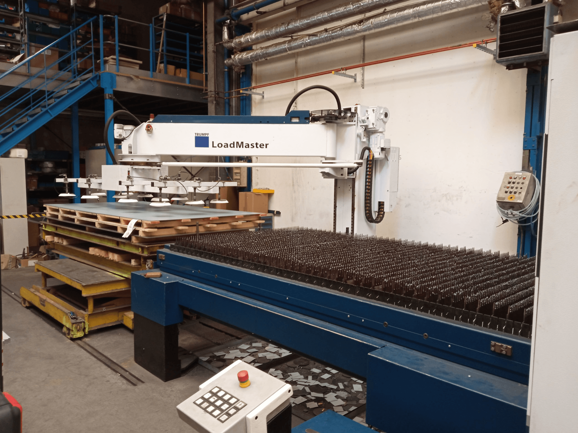 TRUMPF TruLaser 3030 CO₂-Laserschneidanlage in Seitenansicht, mit einem LoadMaster und Materialpaletten.