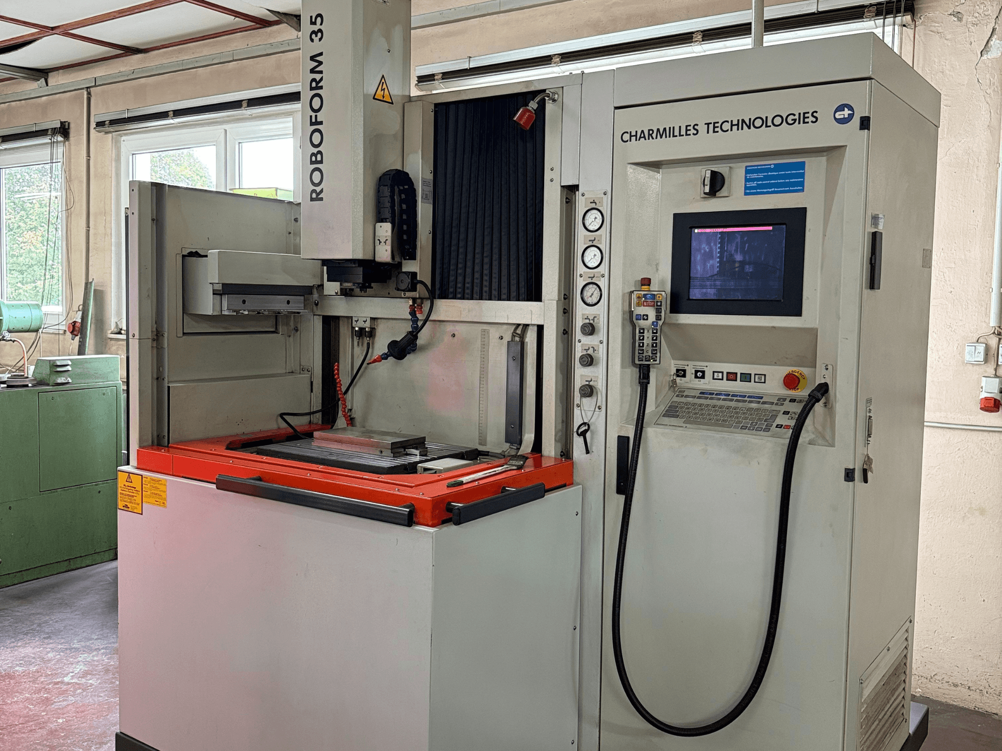 Roboforn 35 von Charmilles Technologies, Vorderansicht, mit Bedienfeld, montierten Werkzeugen und Sicherheitsschildern.