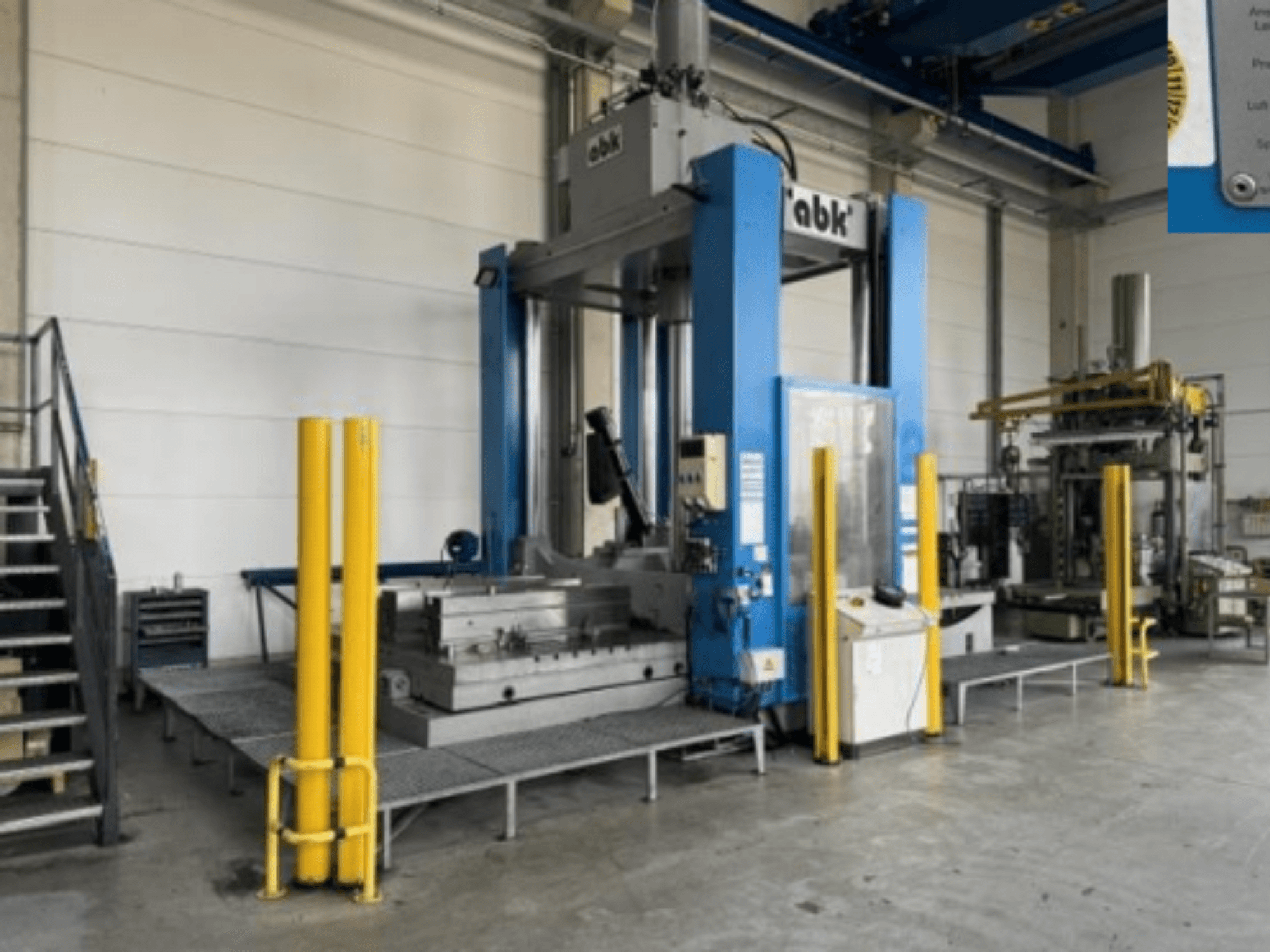Die Werkzeugmaschine ABK abk-TP-20-250 in der Vorderansicht, mit signalgelben Absperrungen und den umgebenden Bearbeitungsanlagen.