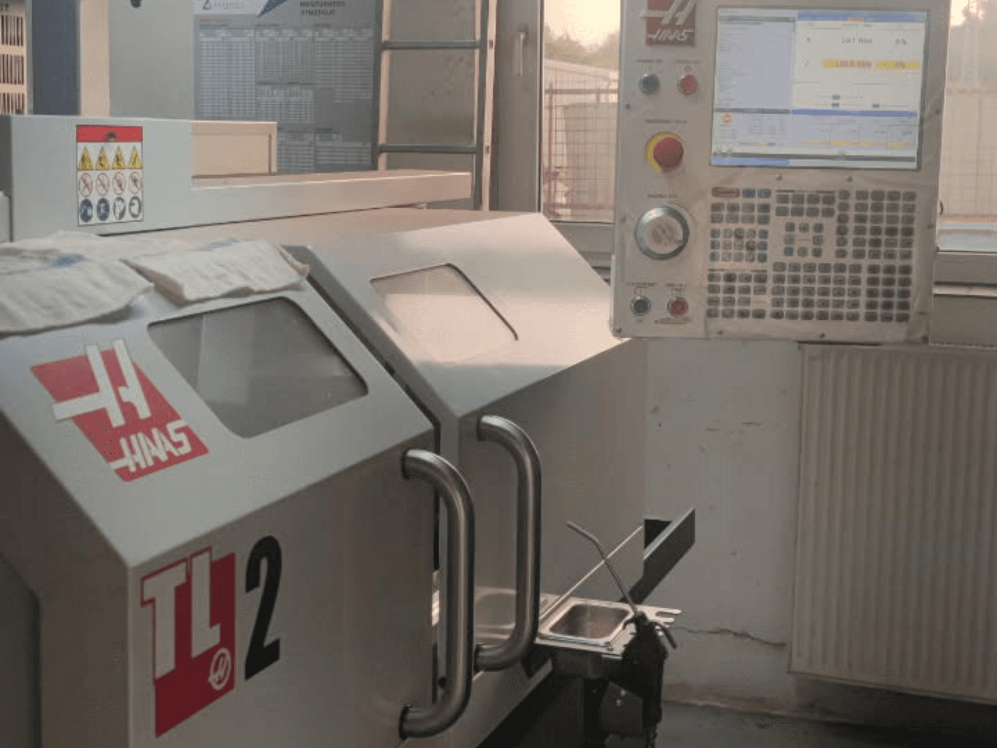 Frontansicht der Haas TL-2 Horizontaldrehmaschine mit Bedienfeld, Metallgehäuse und Sicherheitsschildern.