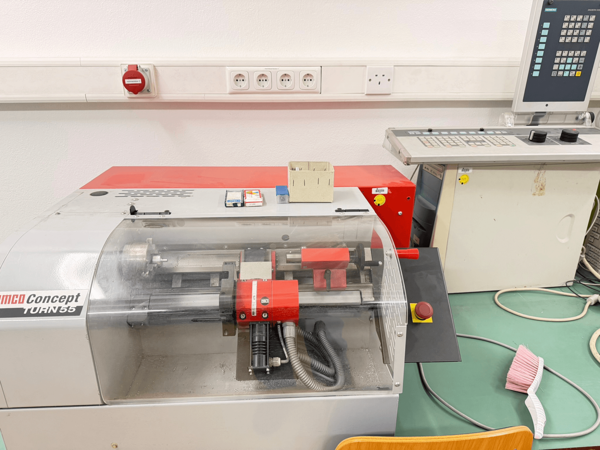 EMCO Concept Turn 55 Horizontaldrehmaschine mit rotem und grauem Äußeren, Vorderansicht mit Bedienelementen und Arbeitsbereich.