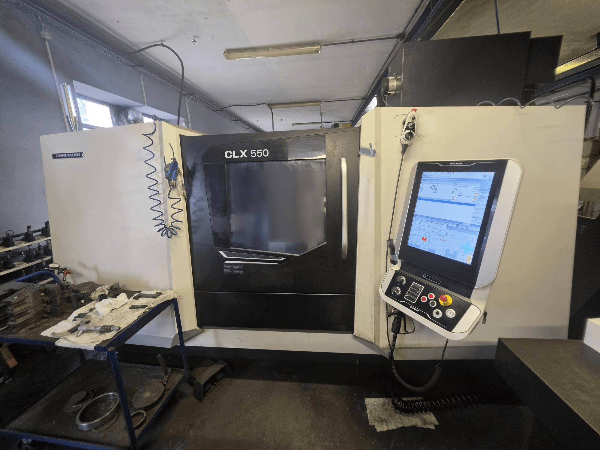 Horizontaldrehmaschine DMG MORI CLX 550 V3, Vorderansicht, mit Blick auf das Bedienfeld und den Arbeitsbereich mit Werkzeugen.